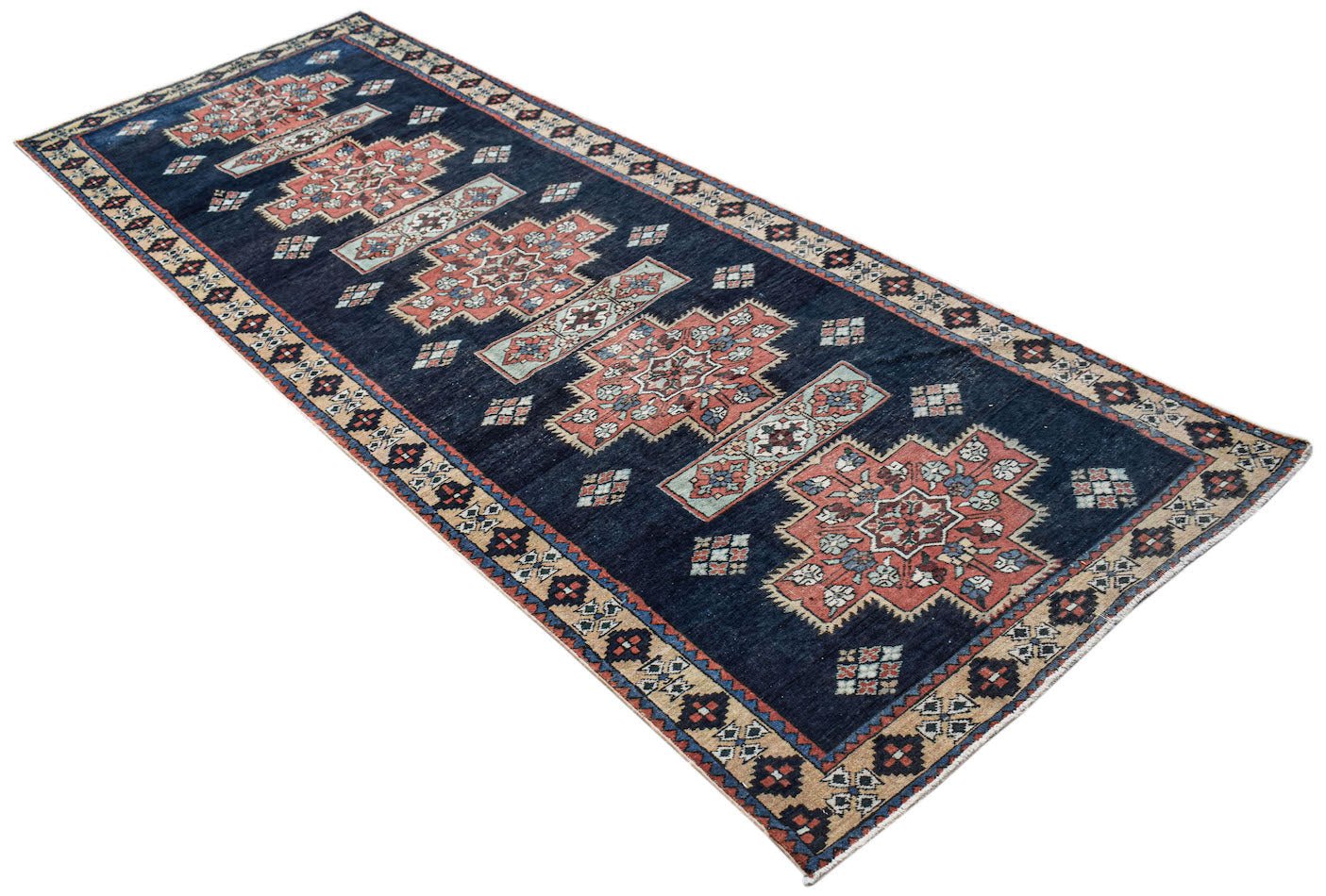 A vintage Persian Ardabil runner featuring geometric floral medallions on a dark blue field.