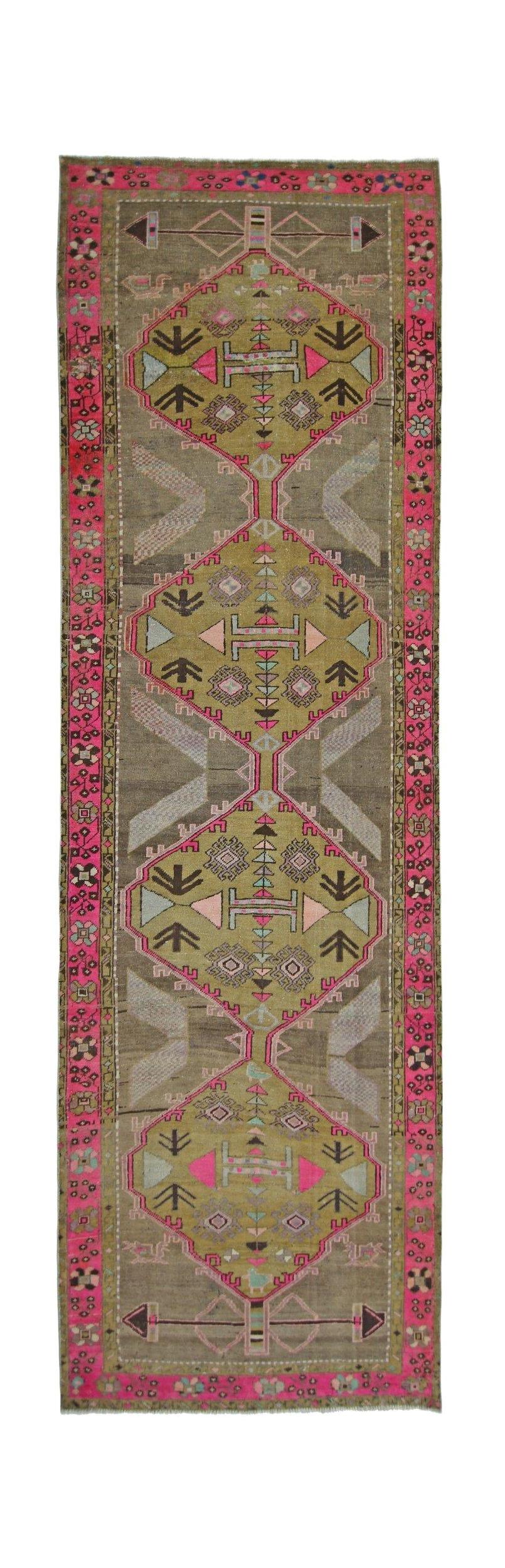 A vintage Persian Serab runner featuring geometric medallions in pink, green, and brown tones.