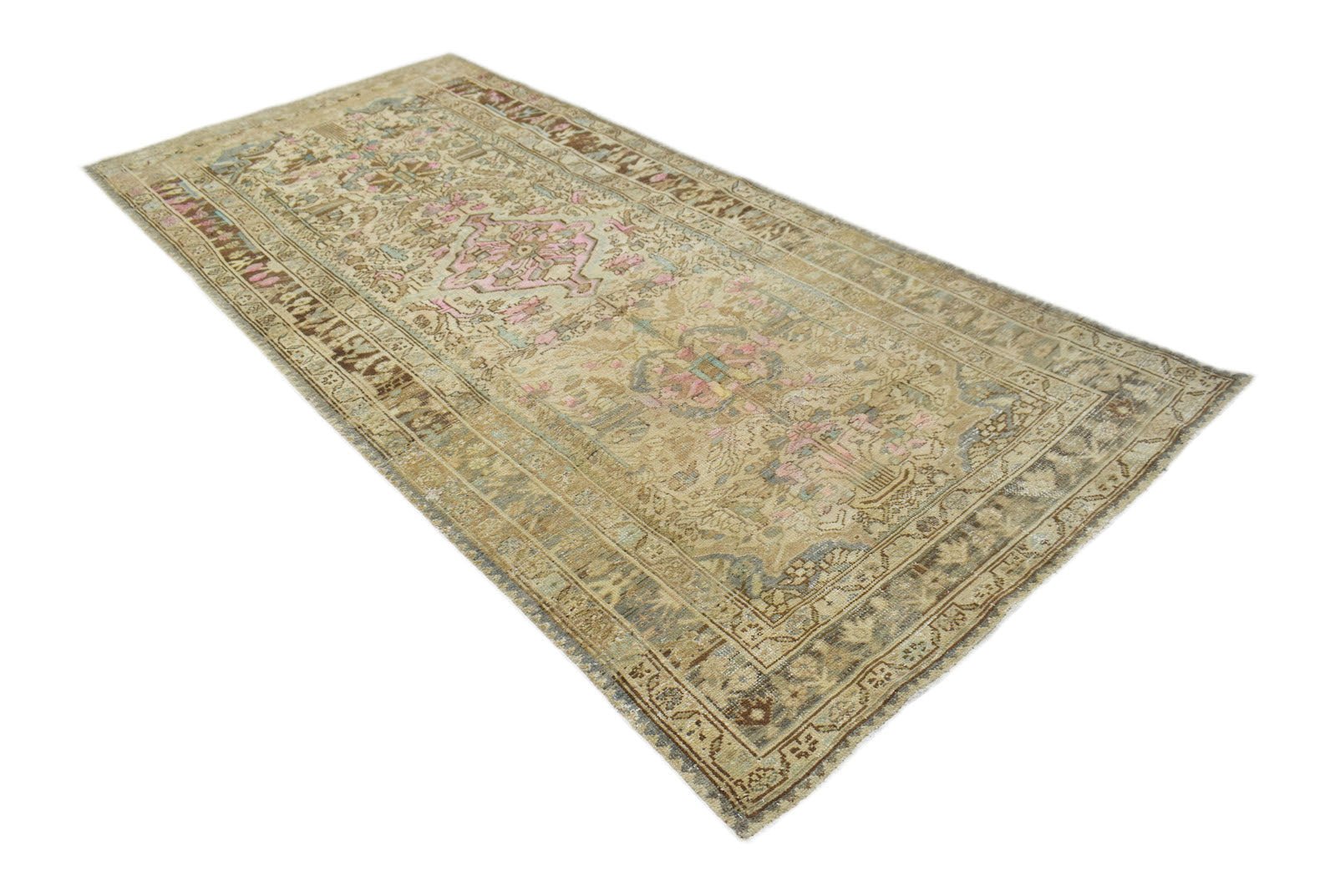 A handwoven vintage Persian runner featuring a faded floral pattern in beige, pink, and blue.