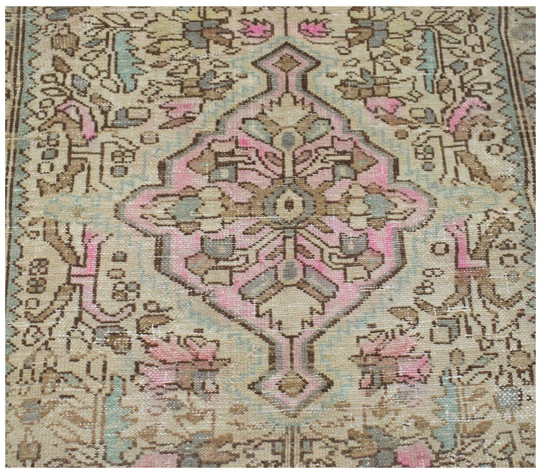 A vintage Persian runner featuring a central pink and beige geometric medallion on a patterned field.