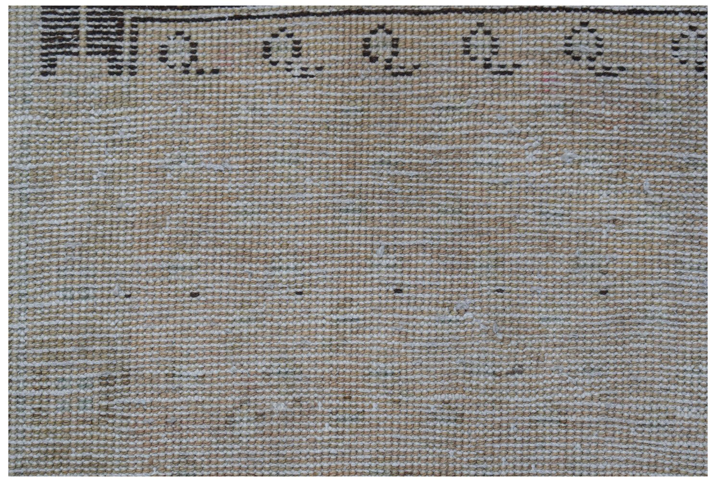 A close-up of a vintage Persian runner featuring a beige wool pile with a dark patterned border.