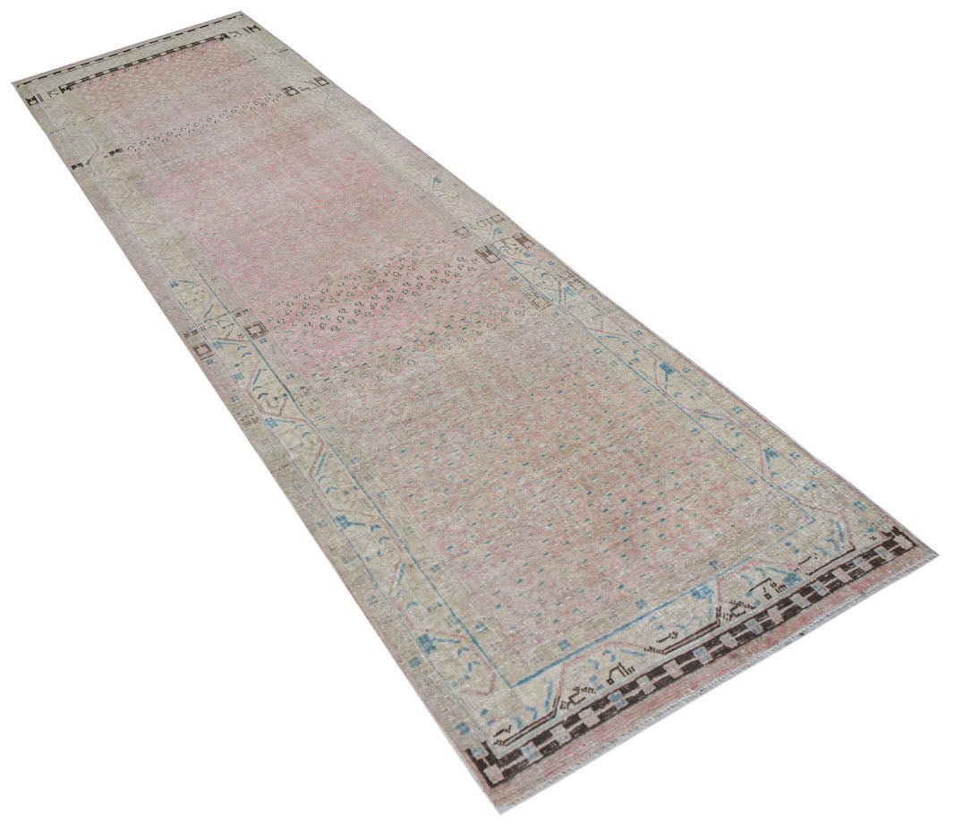 A vintage handwoven Persian runner rug featuring a faded pink and blue patterned design.