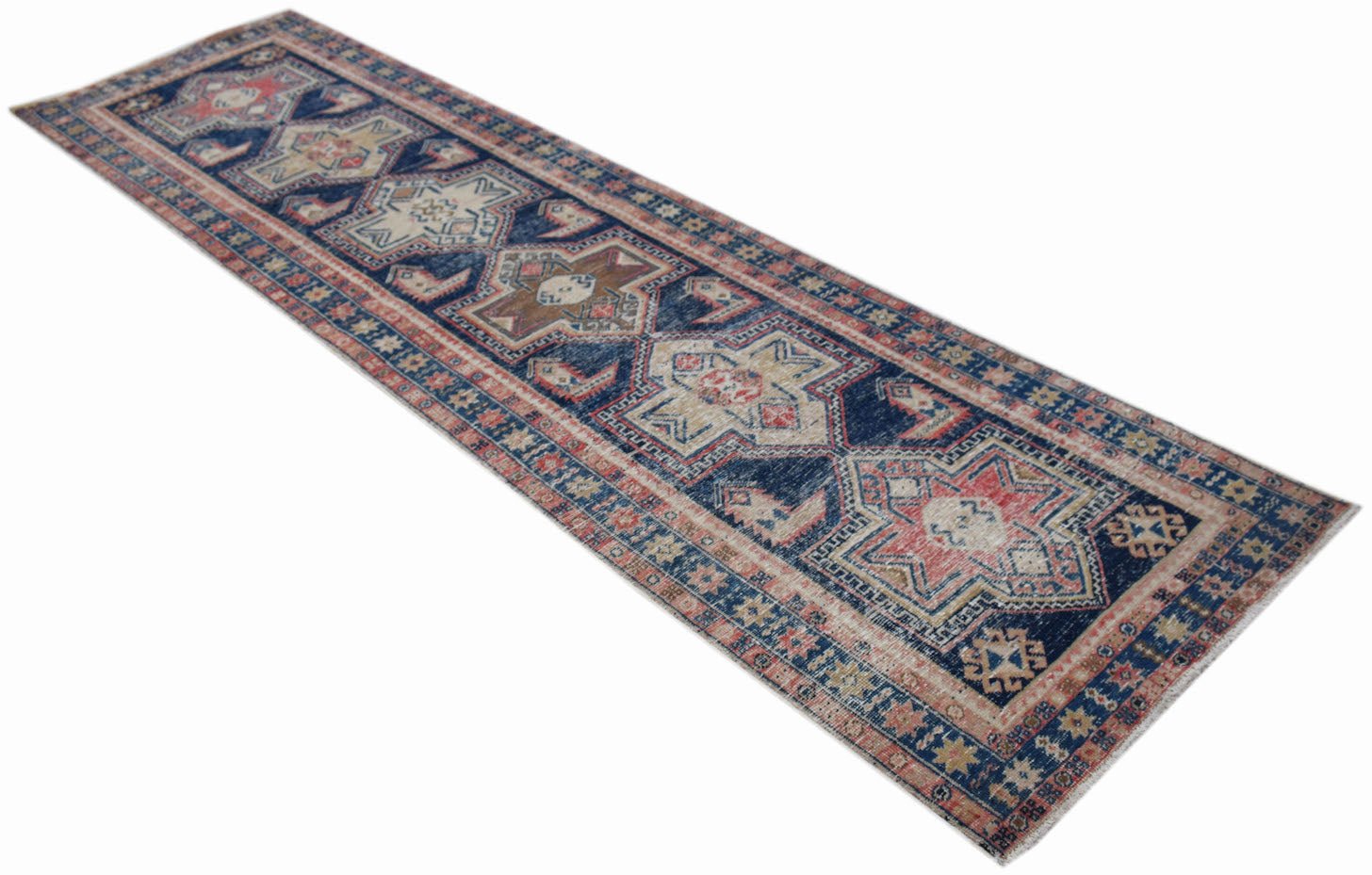 A vintage handwoven Persian runner rug featuring geometric star patterns in blue, red, and cream.