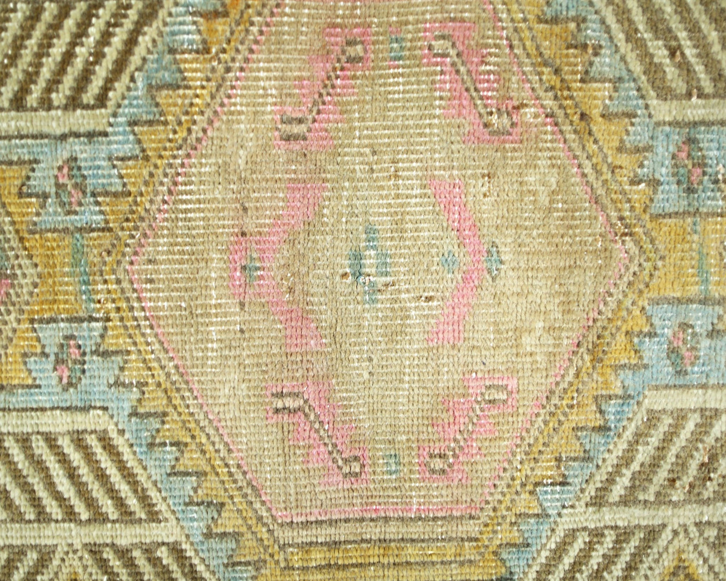 A vintage Persian runner featuring a geometric hexagonal pattern in muted pink, blue, and gold.
