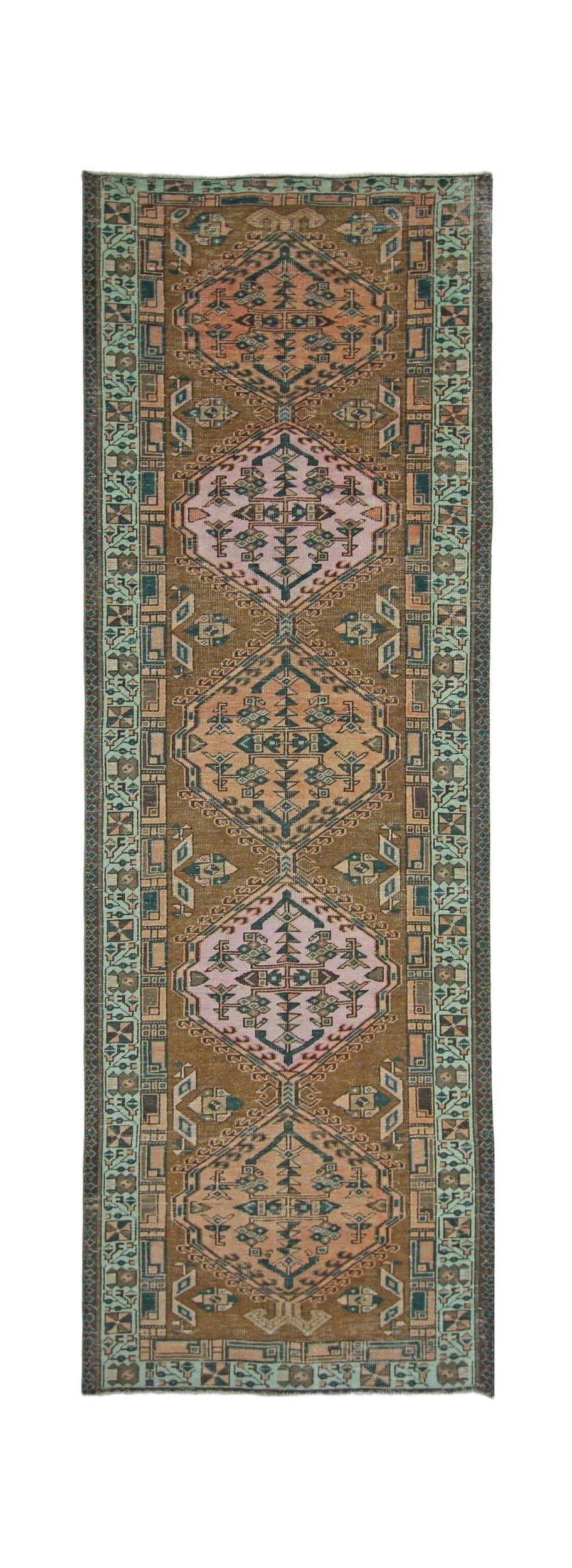 A vintage Persian Serab runner rug featuring geometric medallions in pink and brown tones.