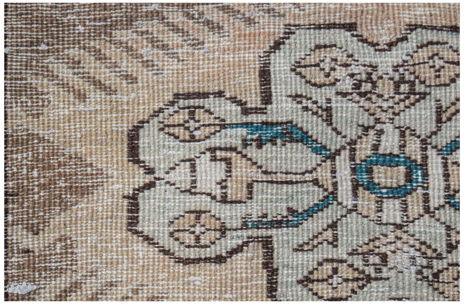 A close-up of a vintage Persian Tabriz runner featuring a faded floral pattern in wool.