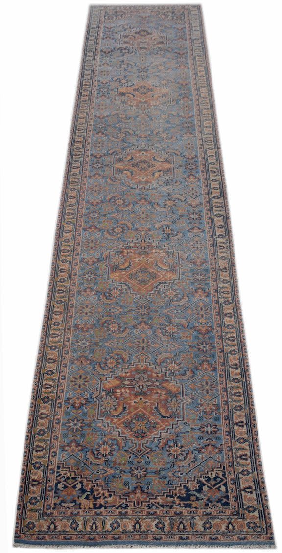 A handwoven vintage Persian runner rug featuring intricate floral patterns in blue and orange tones.