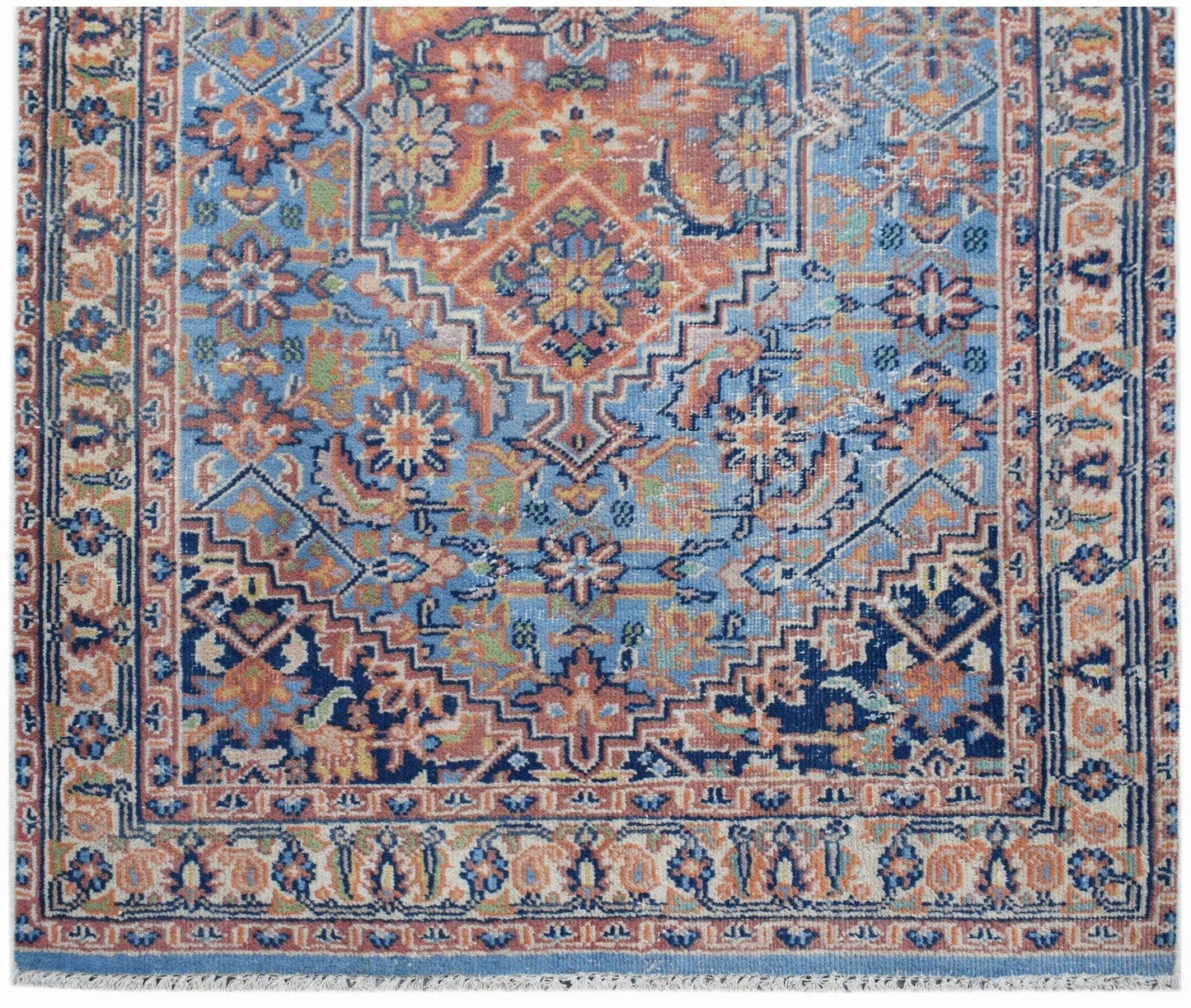 A vintage Persian runner featuring a geometric floral pattern in shades of blue, orange, and cream.