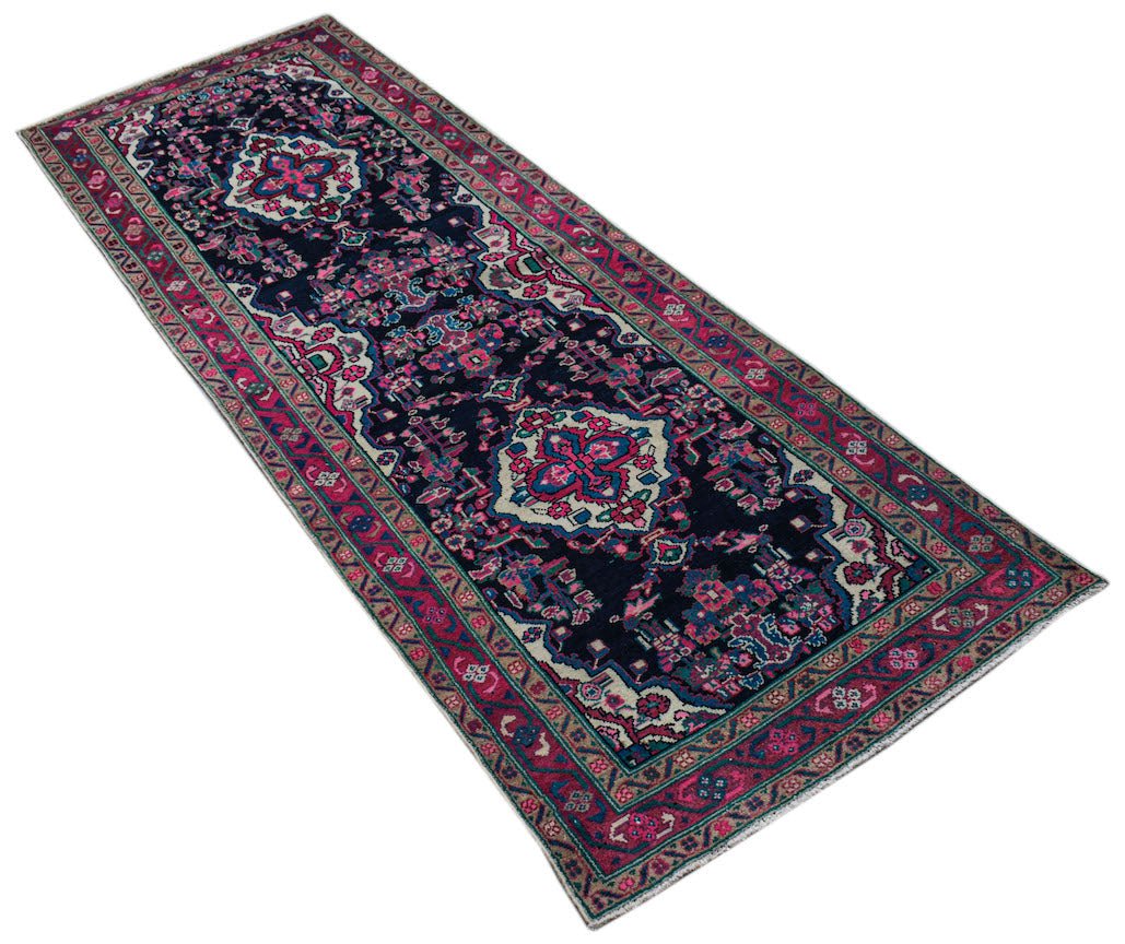 A vintage Persian Hamadan runner featuring a dark blue field with pink and cream floral motifs.