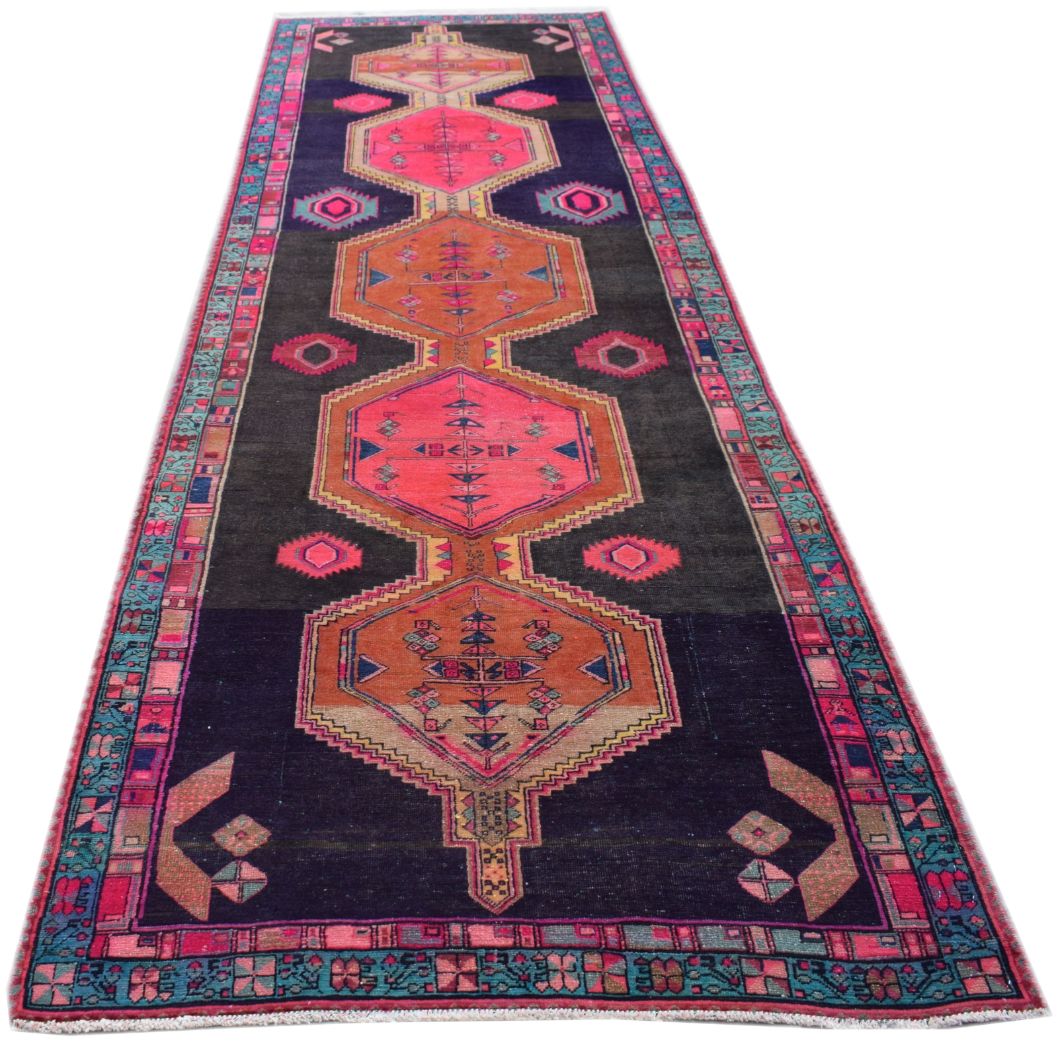 A vintage Persian Hamadan runner rug featuring geometric medallions in pink and orange on black.