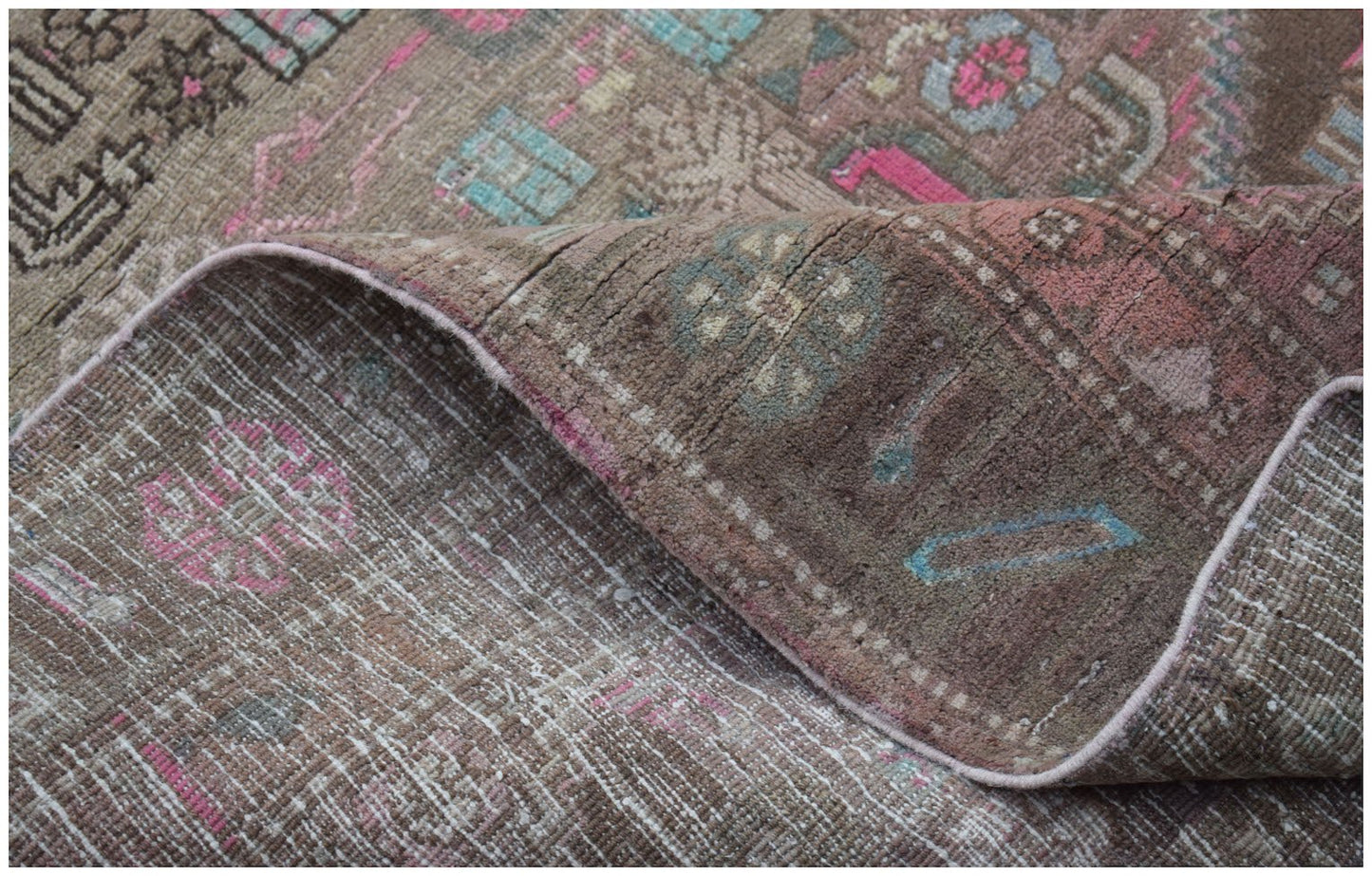 A vintage handwoven Persian Hamadan rug with a worn, faded floral pattern in pink and blue tones.