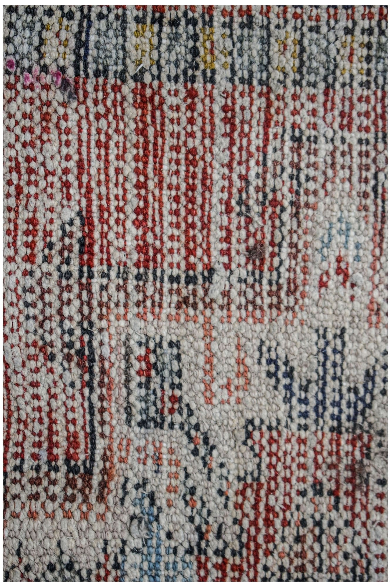 A close-up of a vintage Persian Karaja runner featuring a handwoven wool pattern in red and blue.