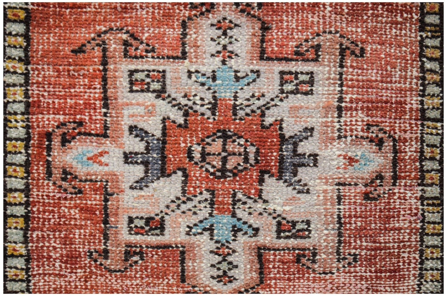 A vintage Persian Karaja runner featuring a geometric medallion pattern in red, blue, and cream.