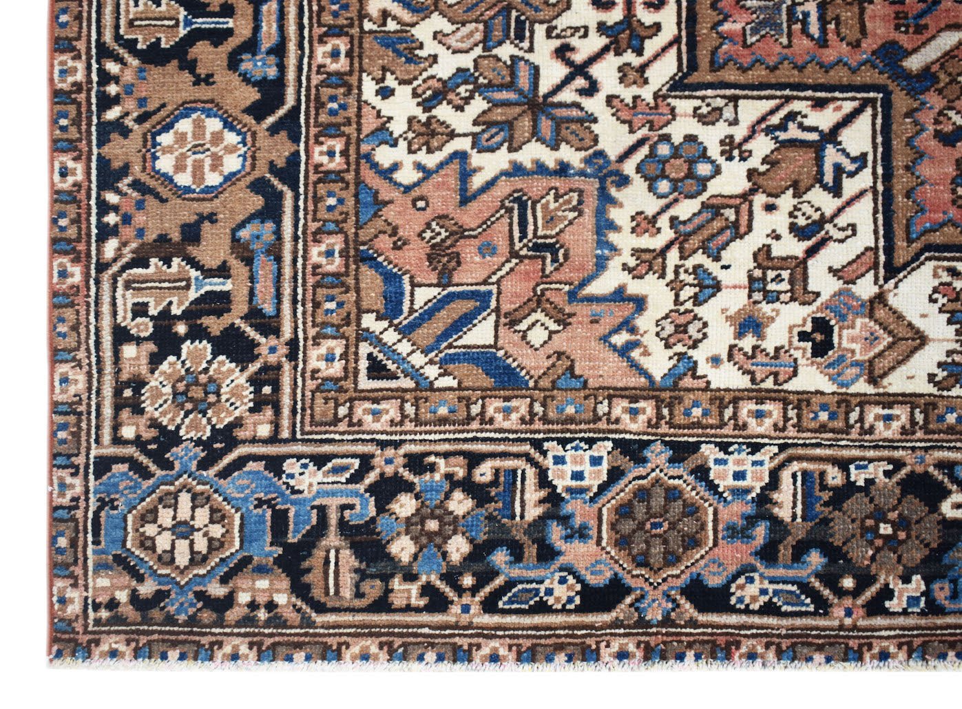 A vintage Persian Heriz rug featuring intricate geometric floral patterns in blue, brown, and cream.