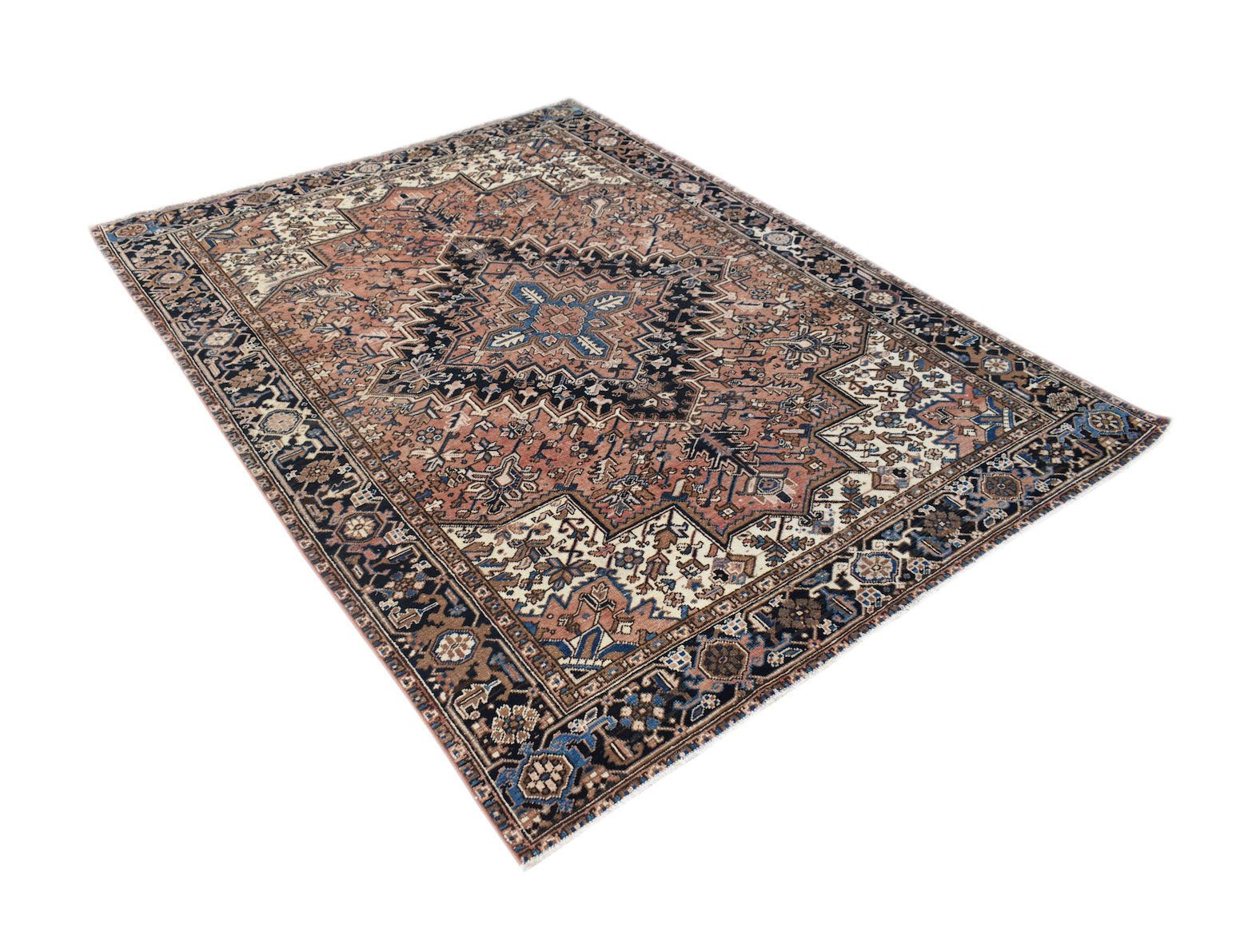 A vintage handwoven Persian Heriz rug featuring a geometric medallion on a terracotta field.