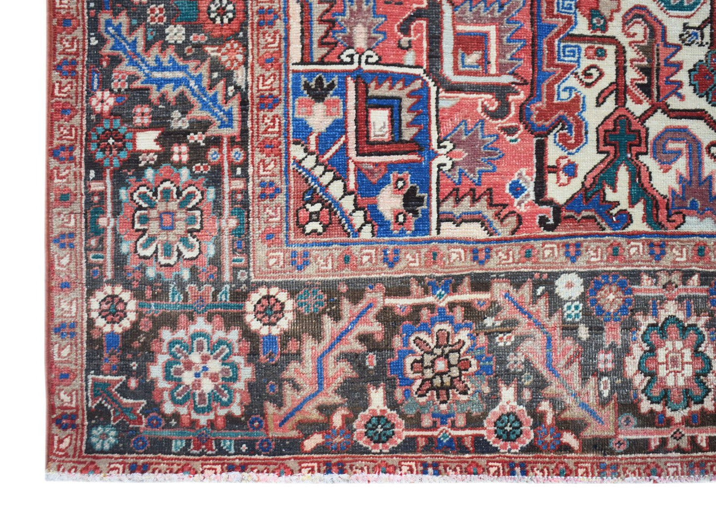 A vintage Persian Heriz rug featuring intricate geometric patterns in red, blue, and cream tones.