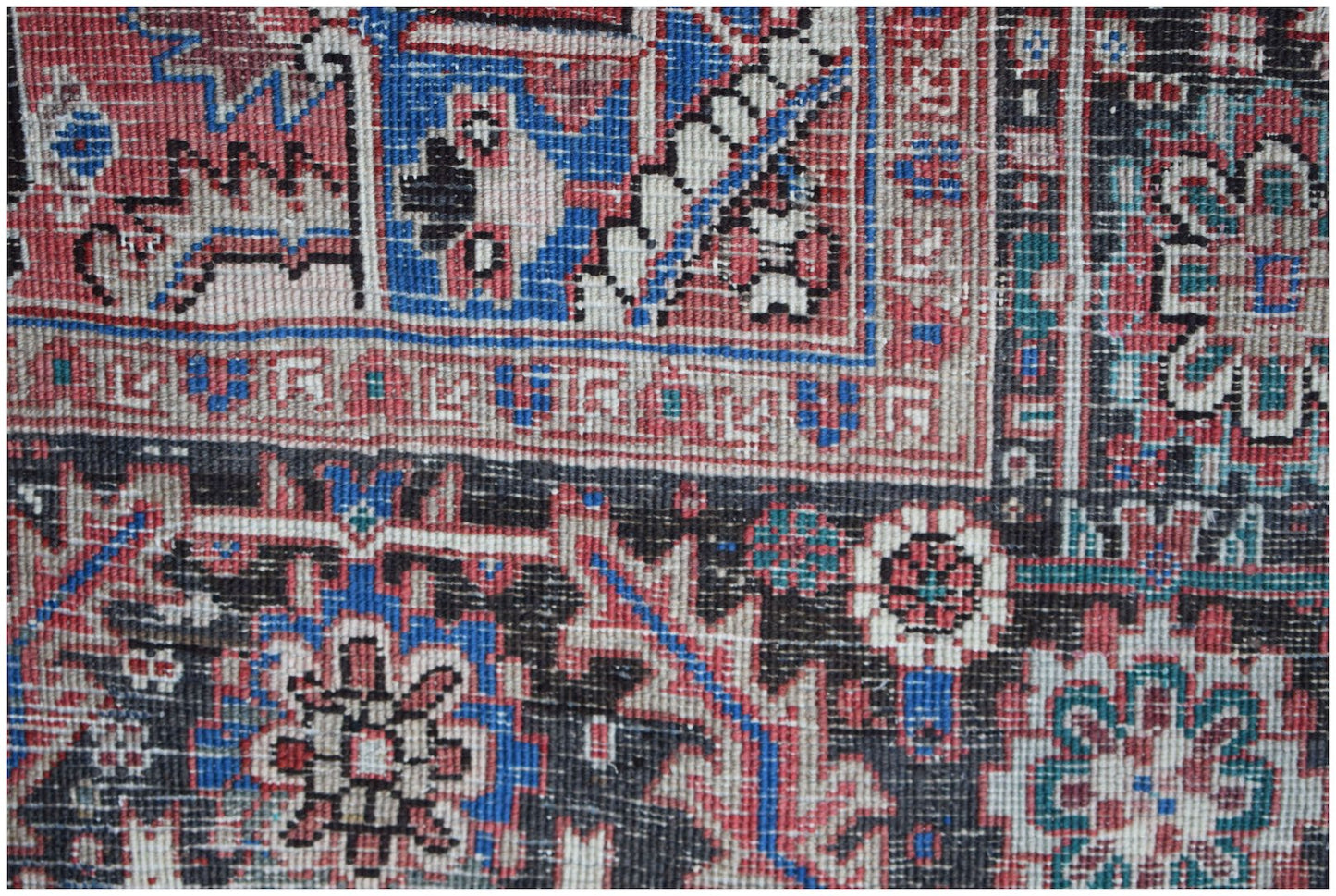 A handwoven vintage Persian Heriz rug featuring intricate geometric patterns in red, blue, and black.