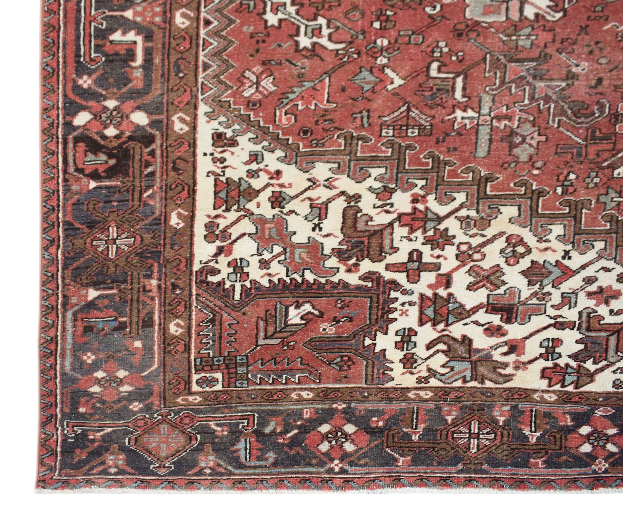 A vintage handwoven Persian Heriz rug featuring a geometric pattern in red, cream, and dark blue.