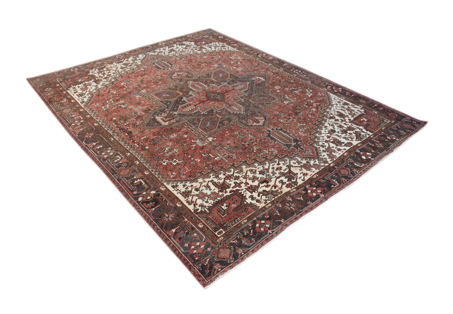 A vintage handwoven Persian Heriz rug featuring a geometric medallion on a red field.