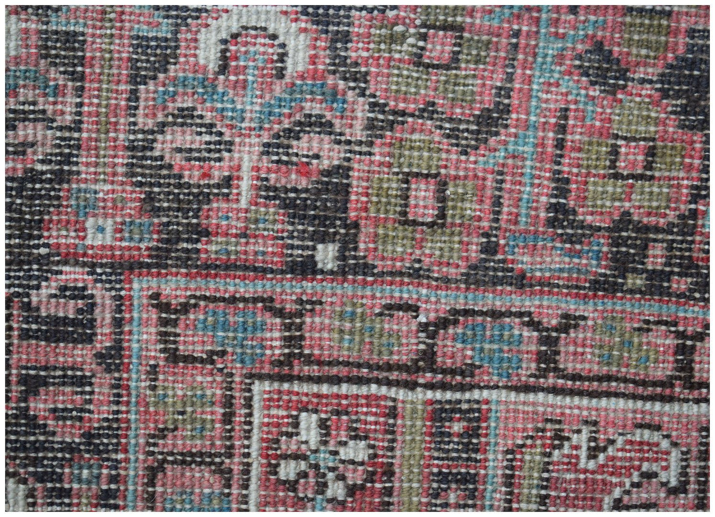 A close-up view of a vintage Persian Heriz rug featuring intricate geometric patterns in wool.