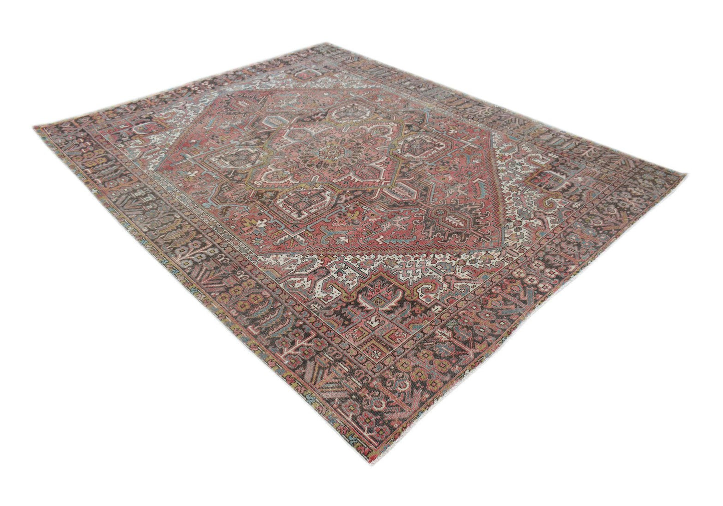 A vintage handwoven Persian Heriz rug featuring a geometric medallion on a faded red field.