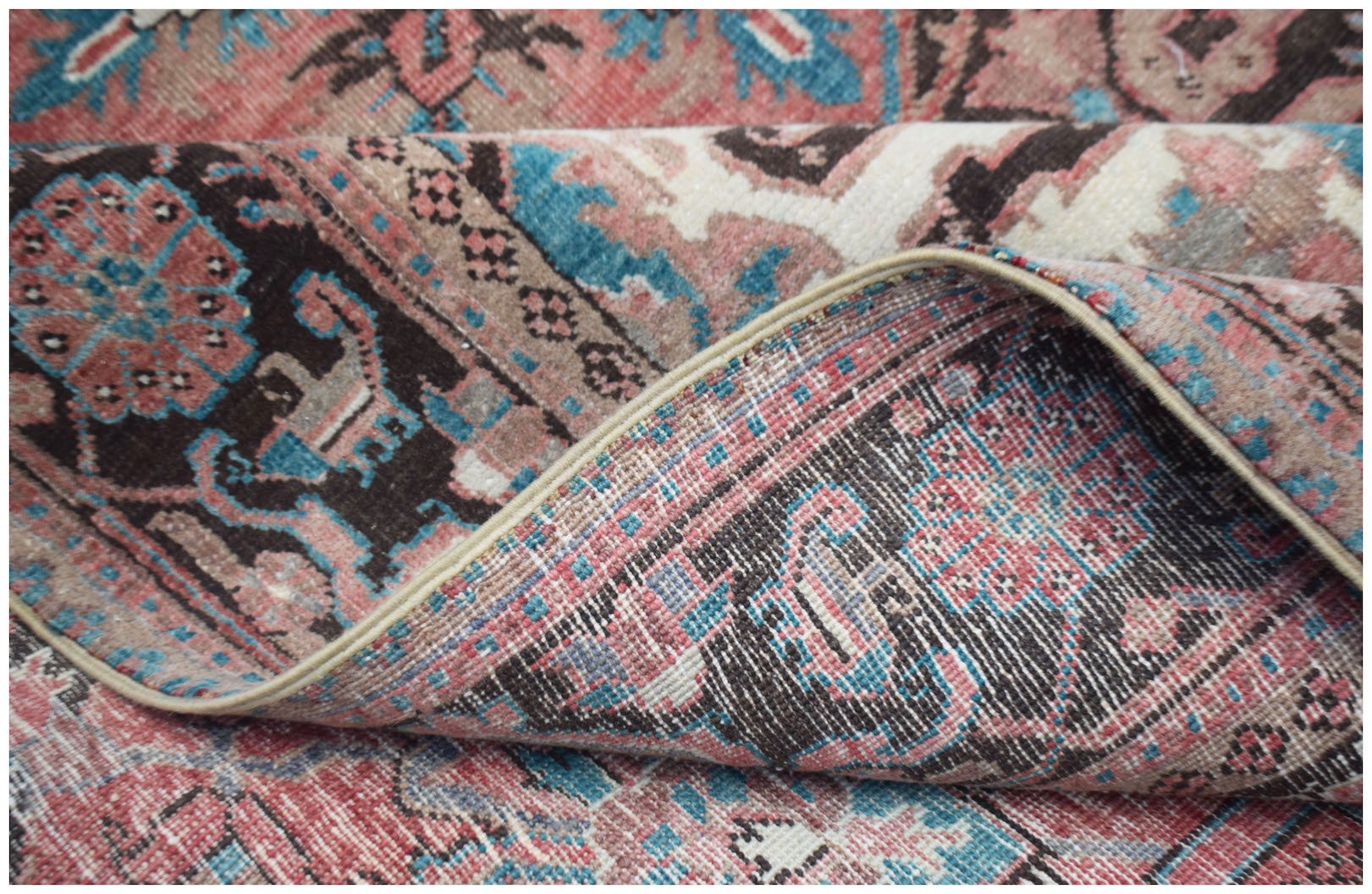 A vintage handwoven Persian Heriz rug featuring a floral pattern in shades of red, blue, and brown.