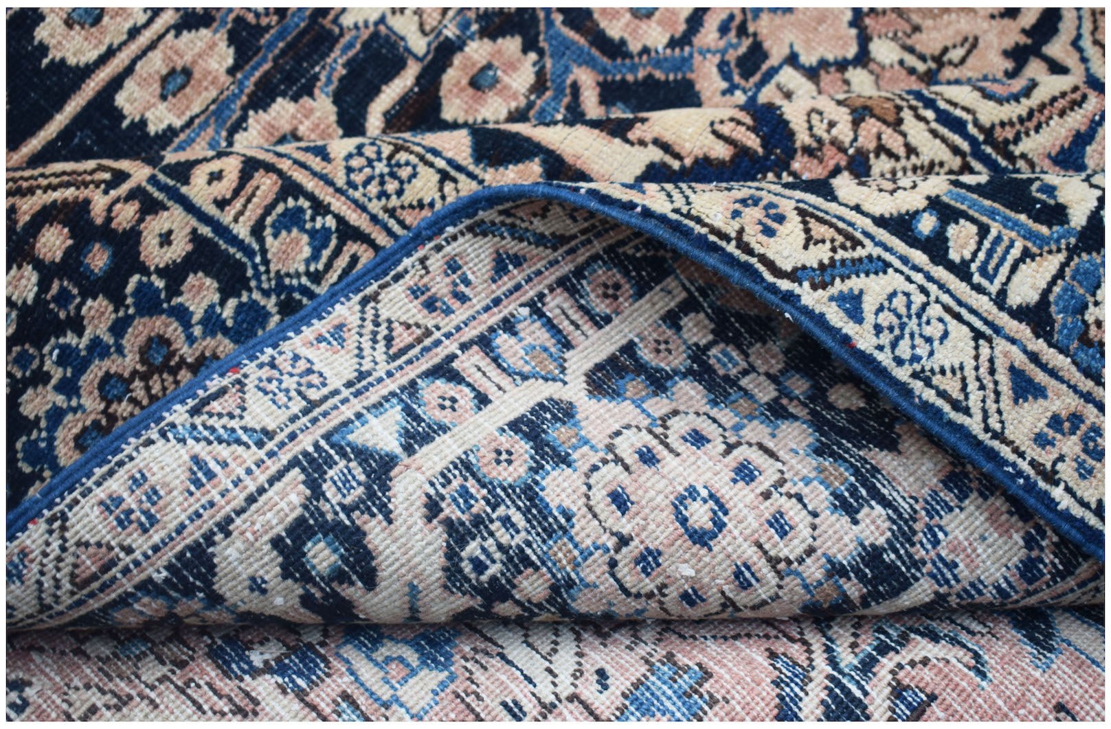 A folded vintage Persian Heriz rug featuring intricate floral patterns in blue and cream tones.