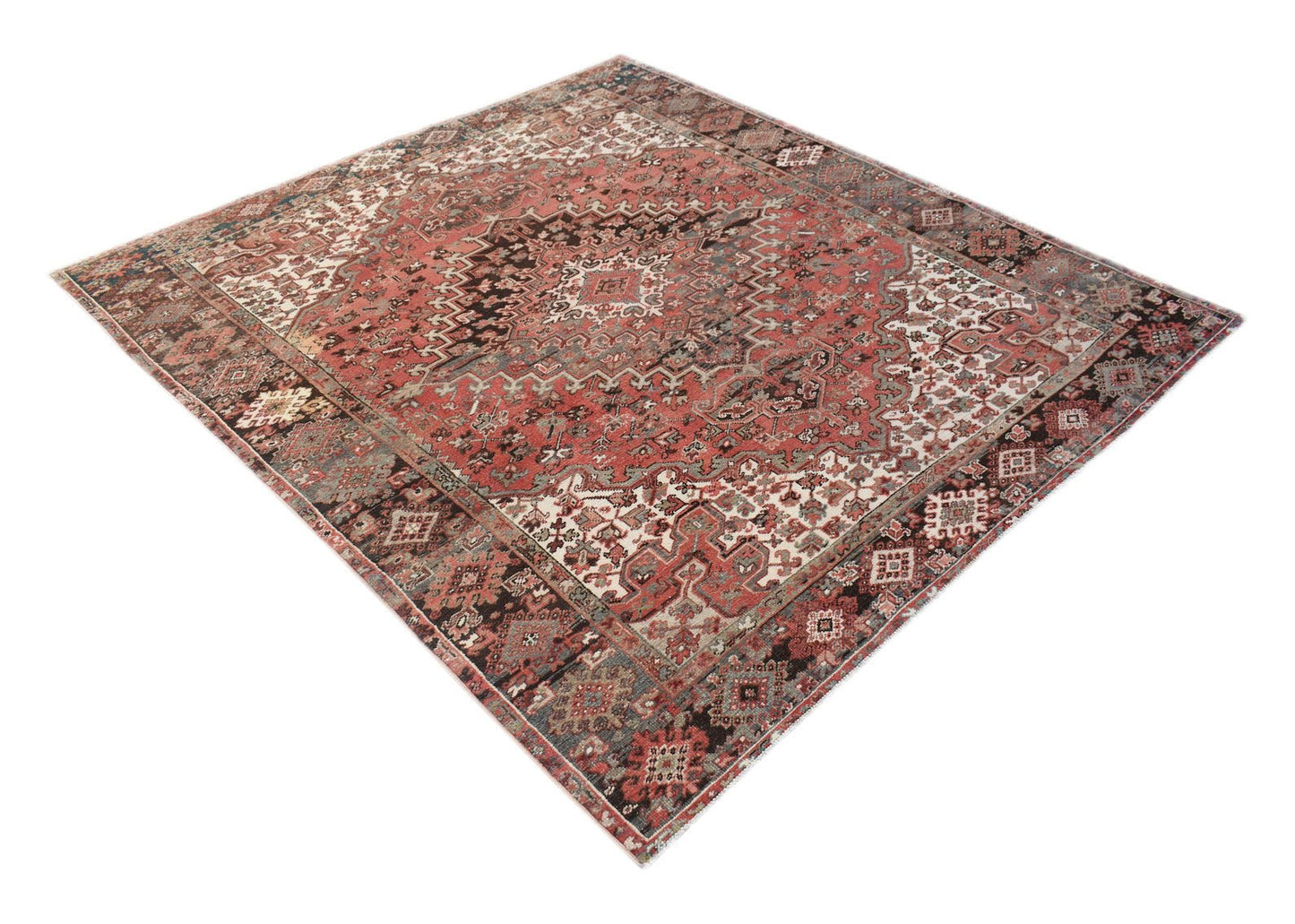 A vintage handwoven Persian Heriz rug featuring a geometric medallion pattern in red and blue tones.