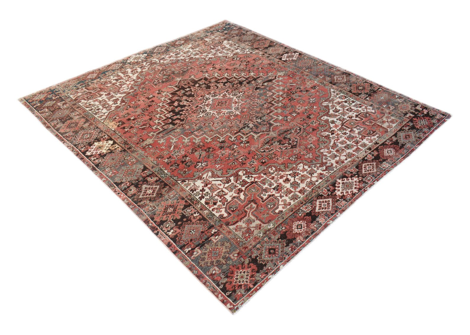 A vintage handwoven Persian Heriz rug featuring a geometric medallion pattern in red and blue tones.