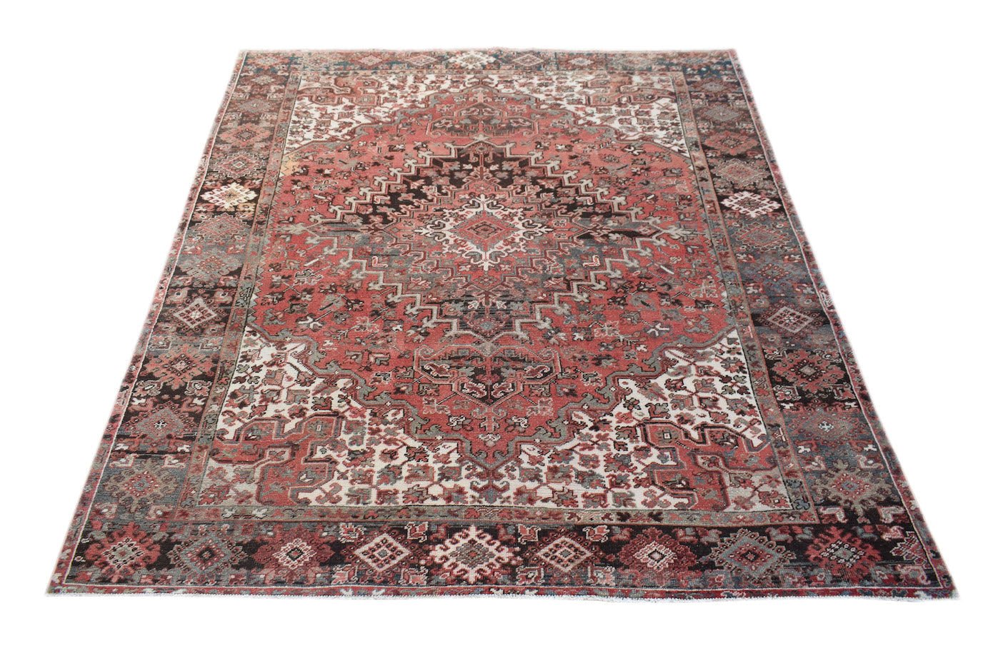 A vintage handwoven Persian Heriz rug featuring a geometric medallion pattern in red and dark tones.