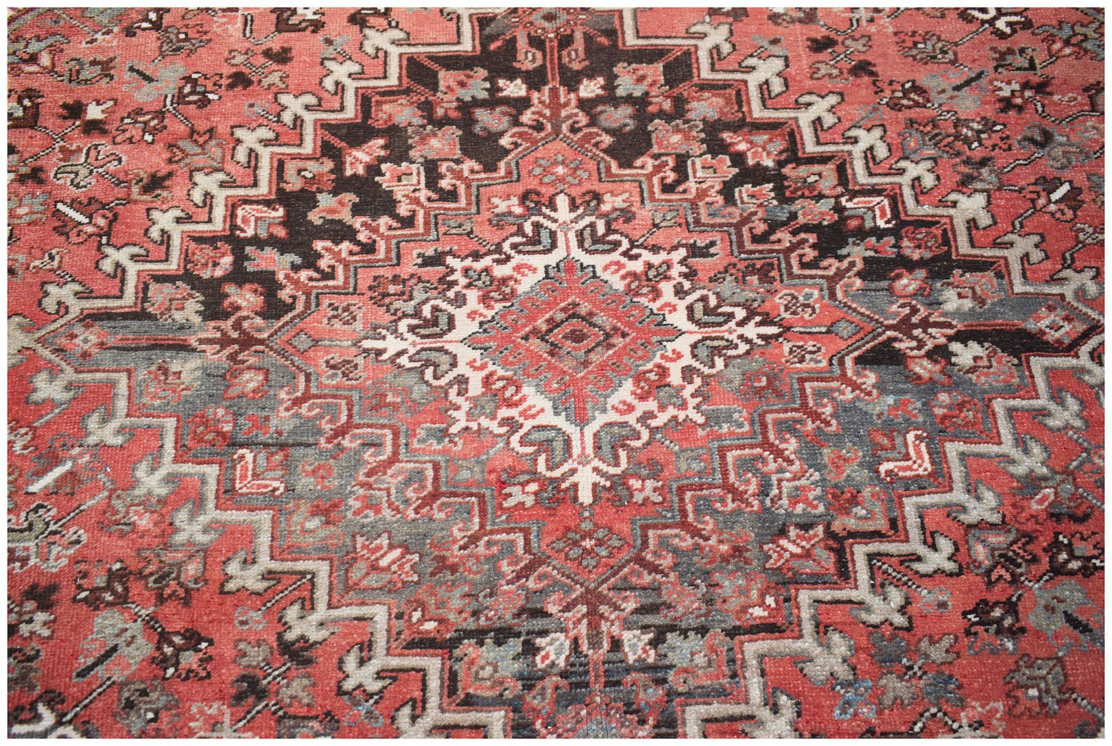 A vintage Persian Heriz rug featuring a geometric medallion pattern in red, black, and cream.