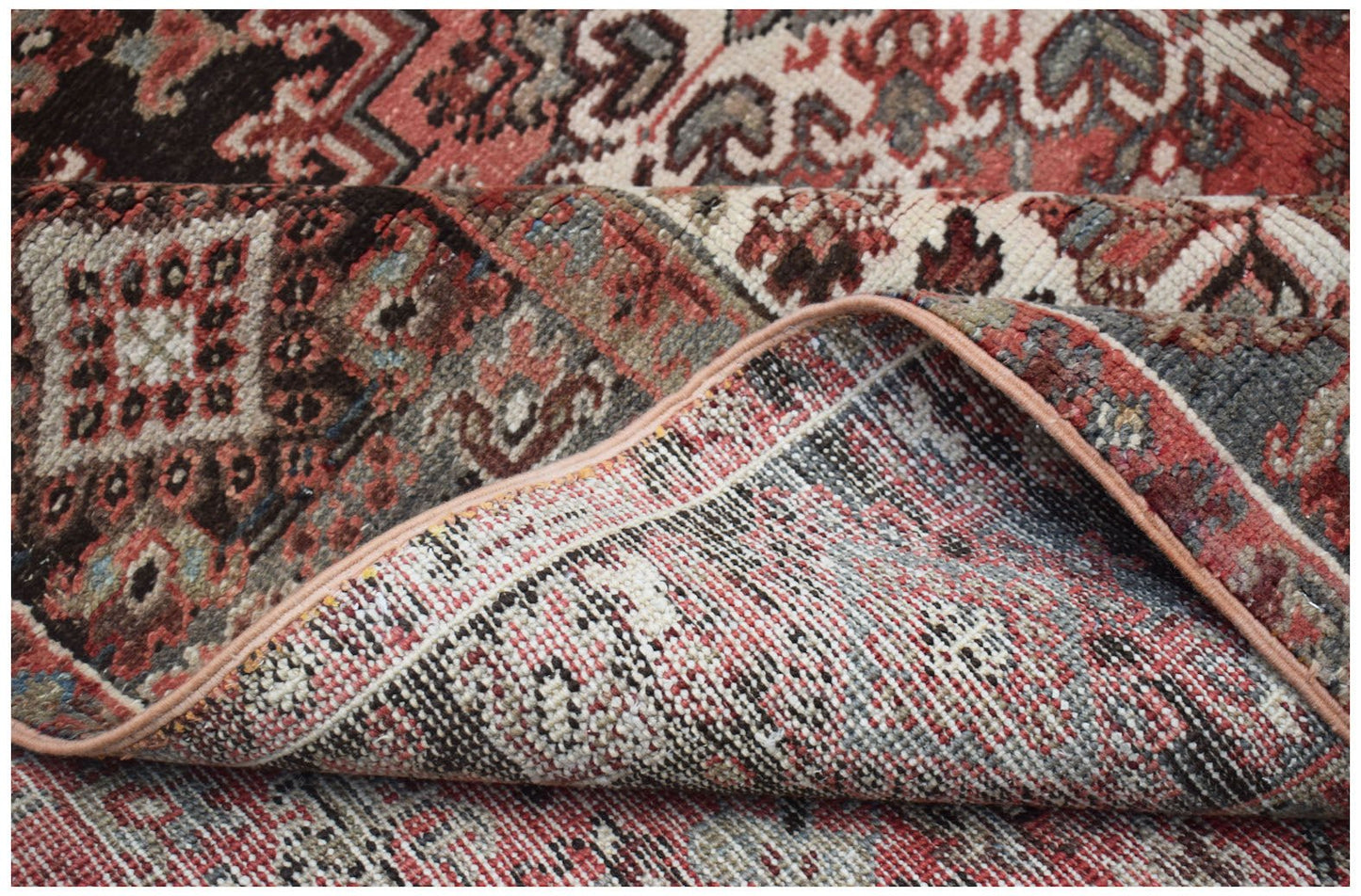A vintage handwoven Persian Heriz rug featuring a traditional geometric pattern in red and grey.