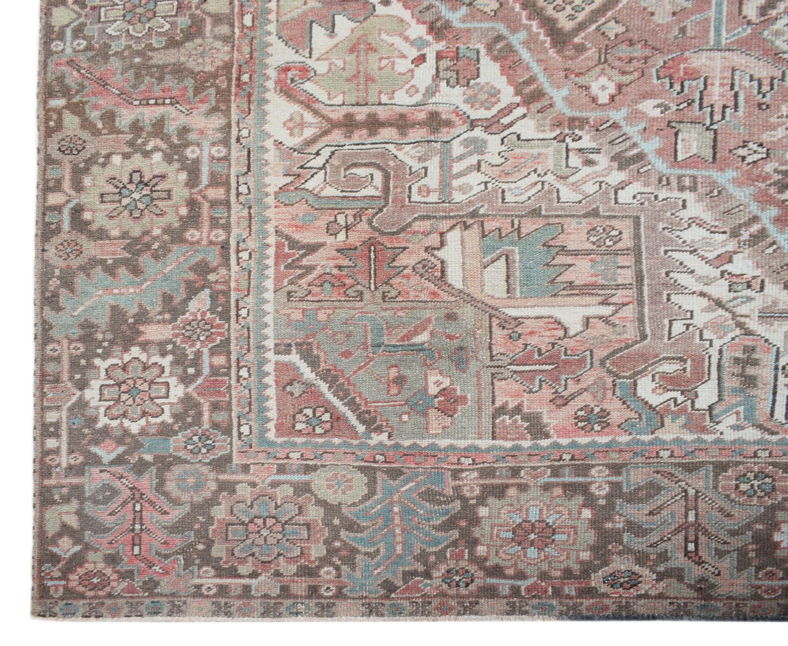 A vintage Persian Heriz rug featuring a geometric floral pattern in muted pink, brown, and blue.