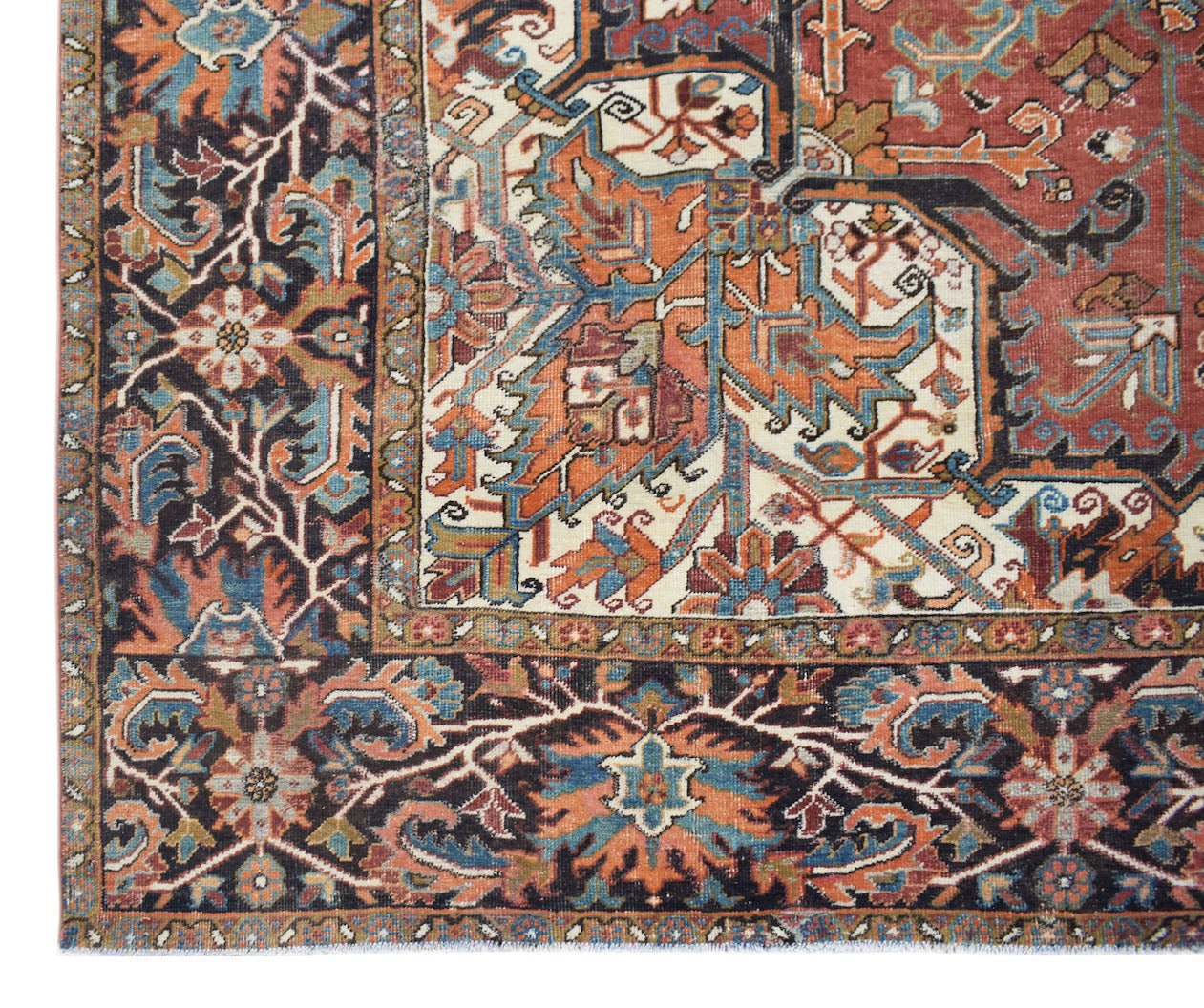 A vintage Persian Heriz rug featuring a geometric floral pattern in rust, blue, and cream tones.