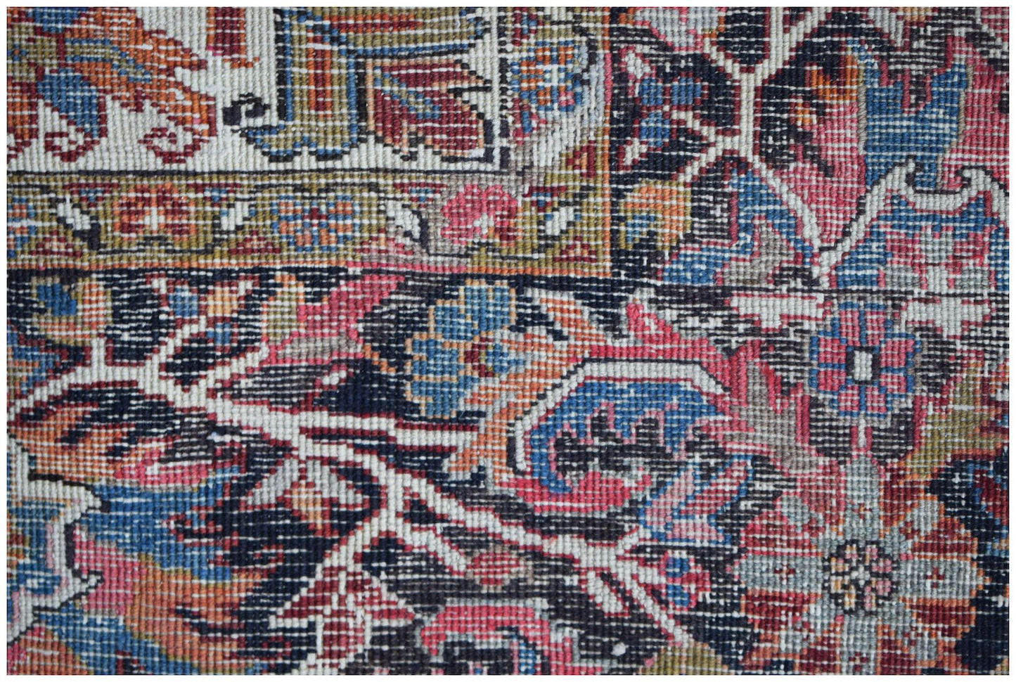 A close-up of a vintage Persian Heriz rug featuring intricate floral patterns in red and blue.