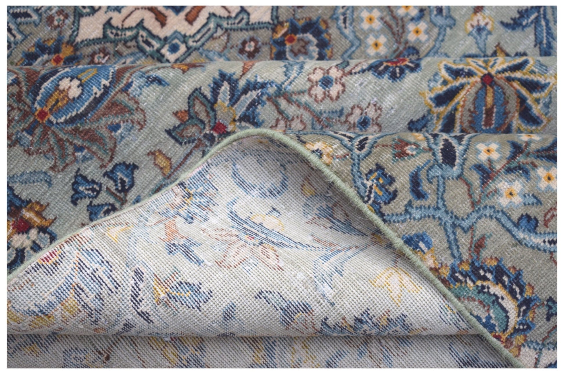 A vintage Persian Kashan rug featuring intricate floral patterns in blue and green tones.