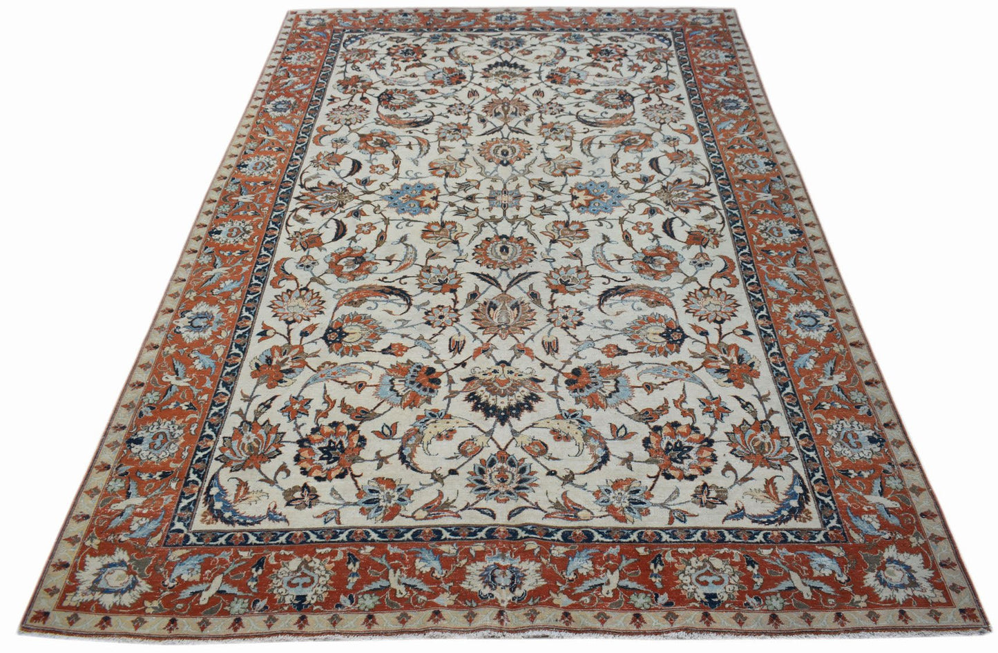 A vintage Persian Kashan rug featuring intricate floral patterns in rust, blue, and cream tones.