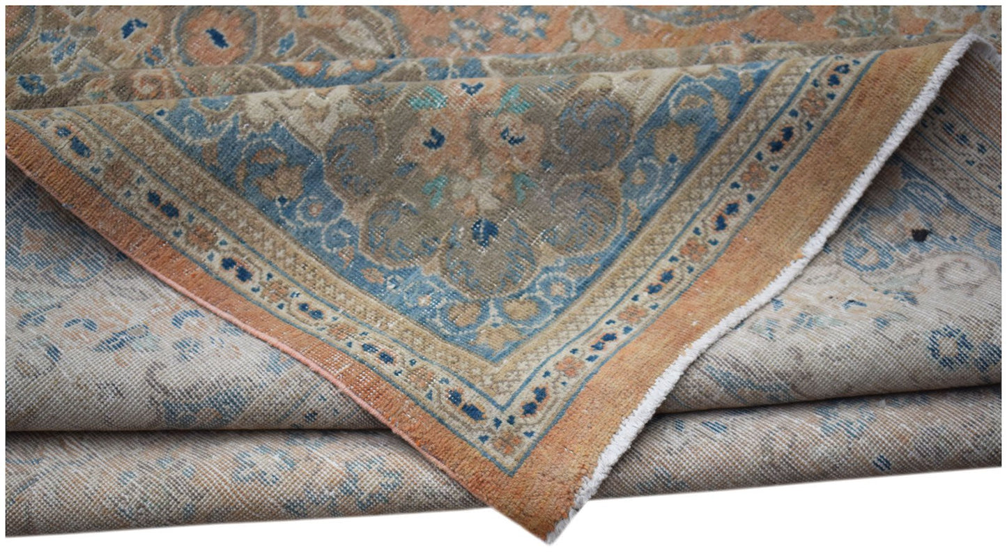 A vintage Persian Kashan rug featuring a faded floral pattern in shades of blue and orange.