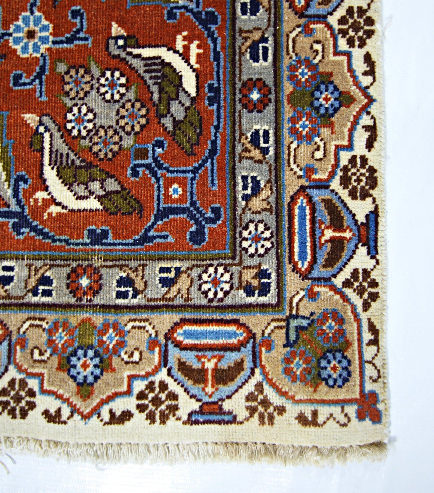 A corner view of a vintage Persian Kashmar rug featuring intricate bird and floral motifs.