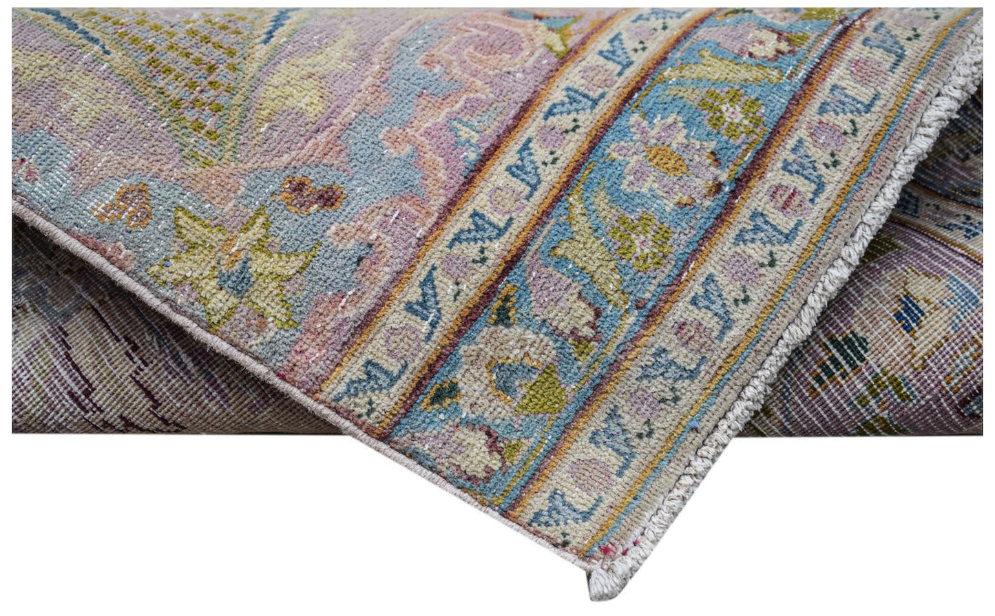 A folded vintage Persian Kerman runner featuring intricate floral patterns in soft pastel tones.
