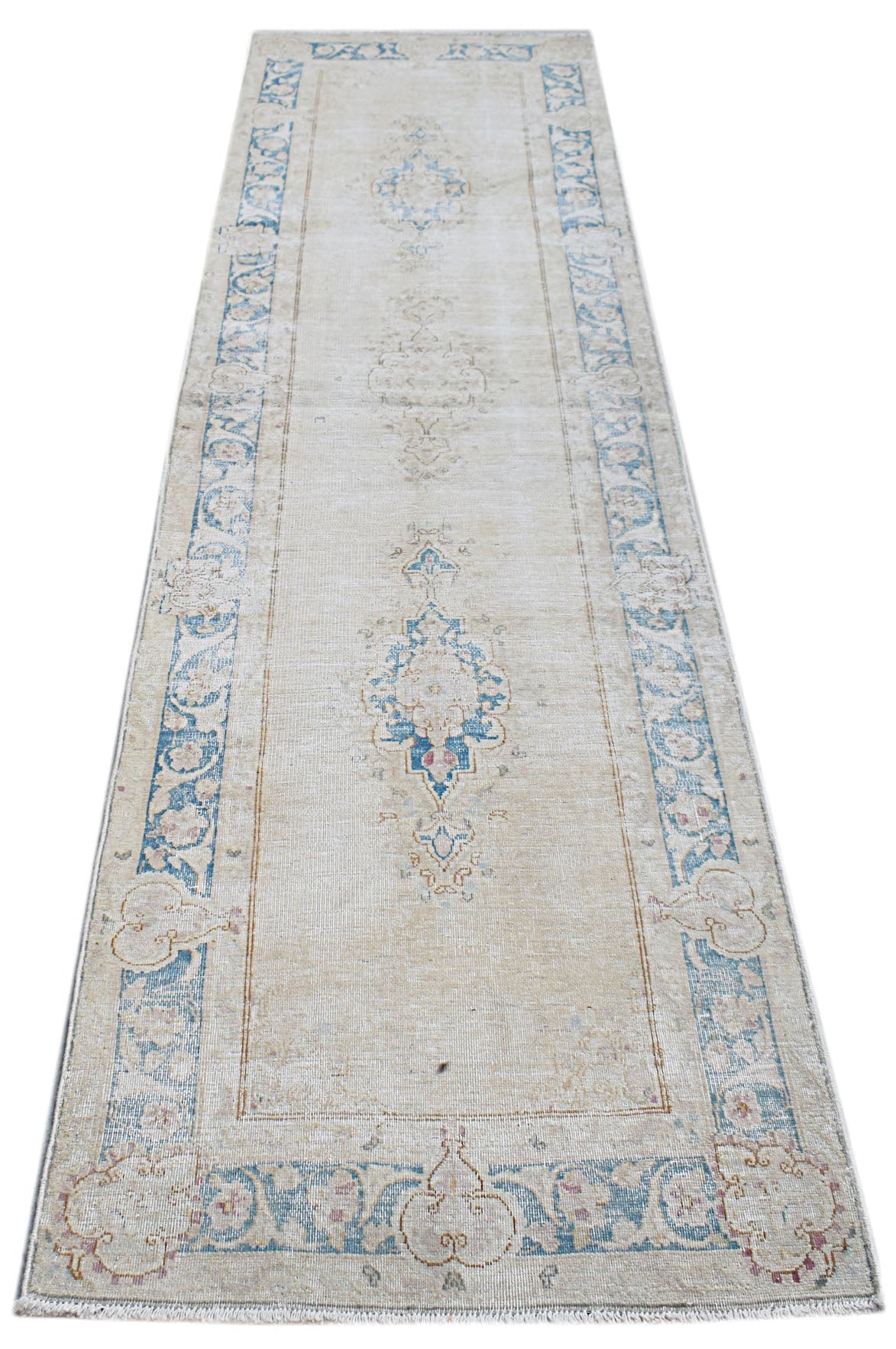 A vintage Persian Kerman runner rug featuring a central blue medallion on a beige field.