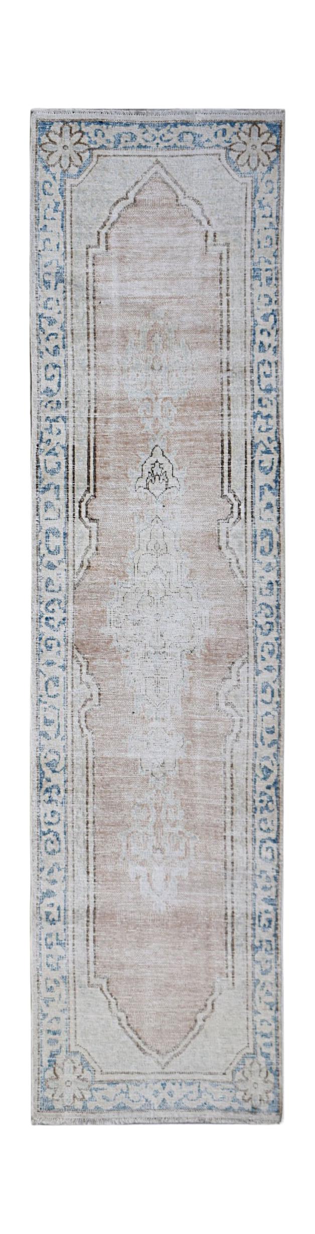 A vintage Persian Kerman runner rug featuring a central medallion and floral border in soft tones.