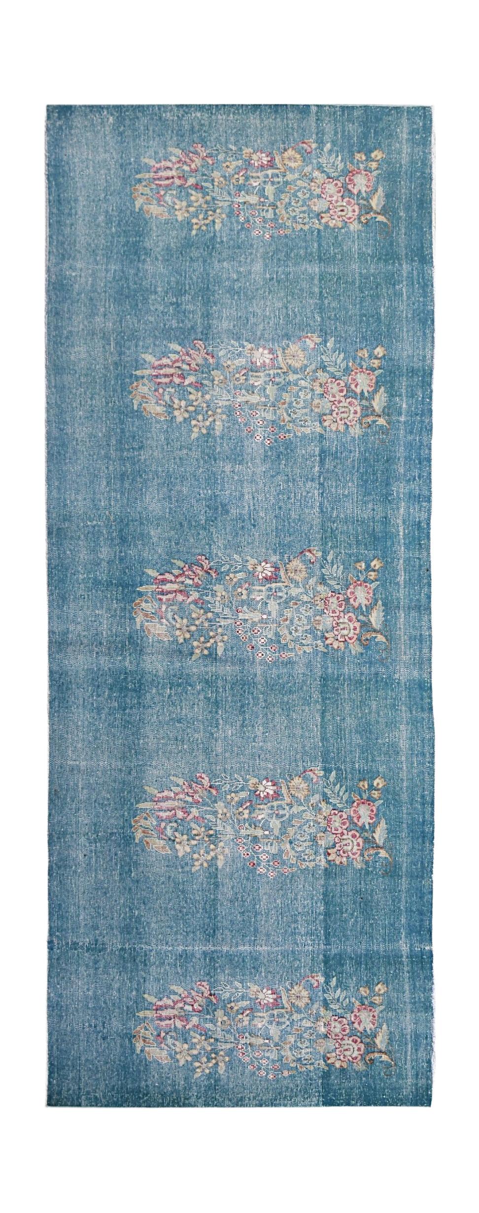 A vintage Persian Kerman runner featuring repeating floral motifs on a blue field.