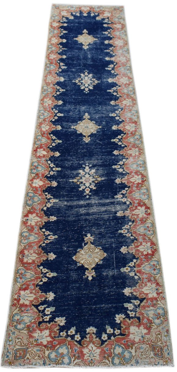 A vintage Persian Kerman runner featuring a deep blue field with floral medallions and borders.
