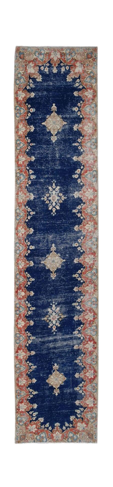 A vintage Persian Kerman runner featuring a deep blue field with a central floral medallion.
