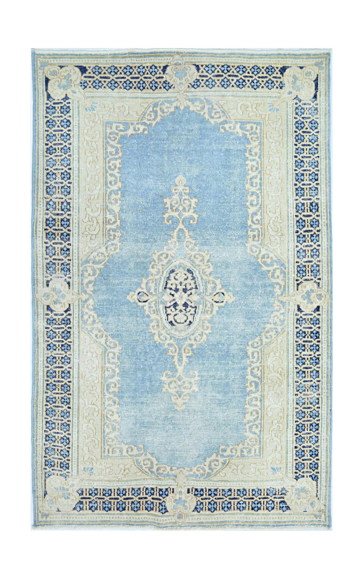 A vintage Persian Kerman rug featuring a central medallion and floral motifs in blue and cream.
