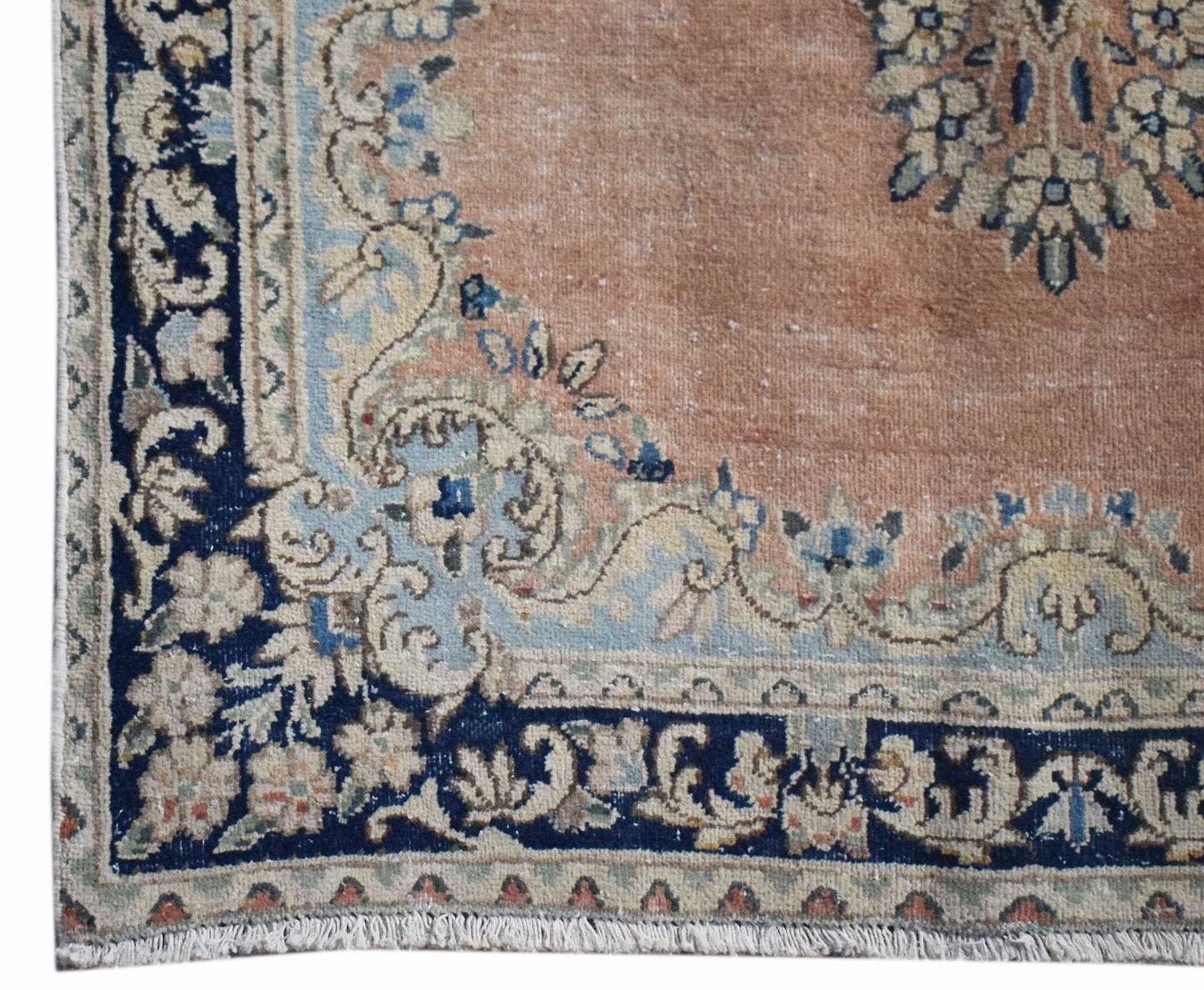 A vintage Persian Kerman rug featuring a floral medallion design in soft peach and navy blue.