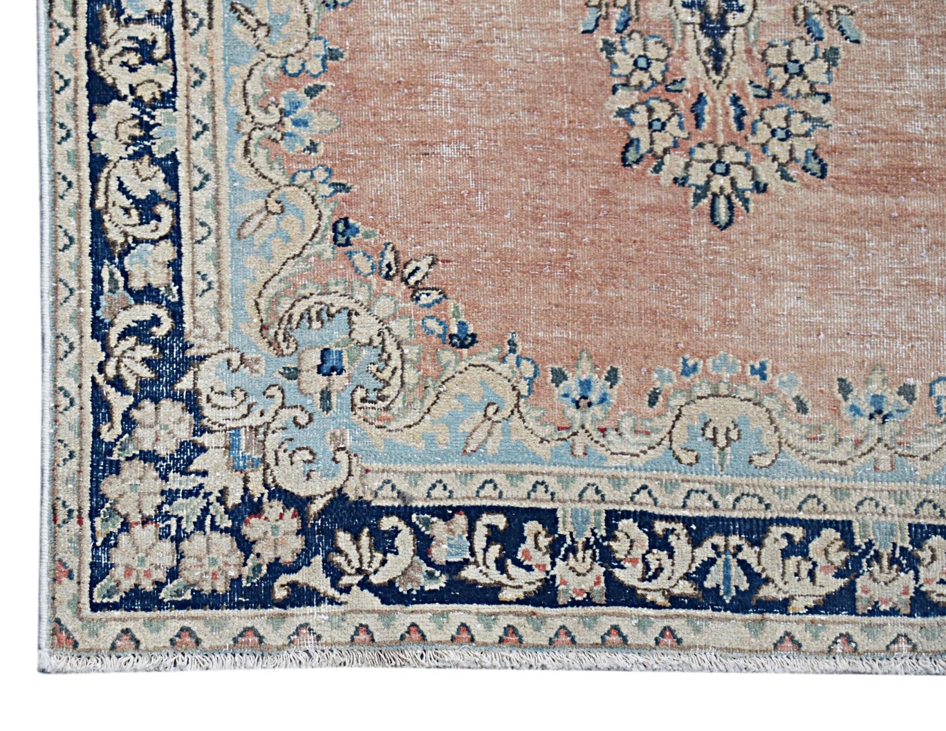 A vintage Persian Kerman rug featuring a soft peach field with intricate blue floral borders.