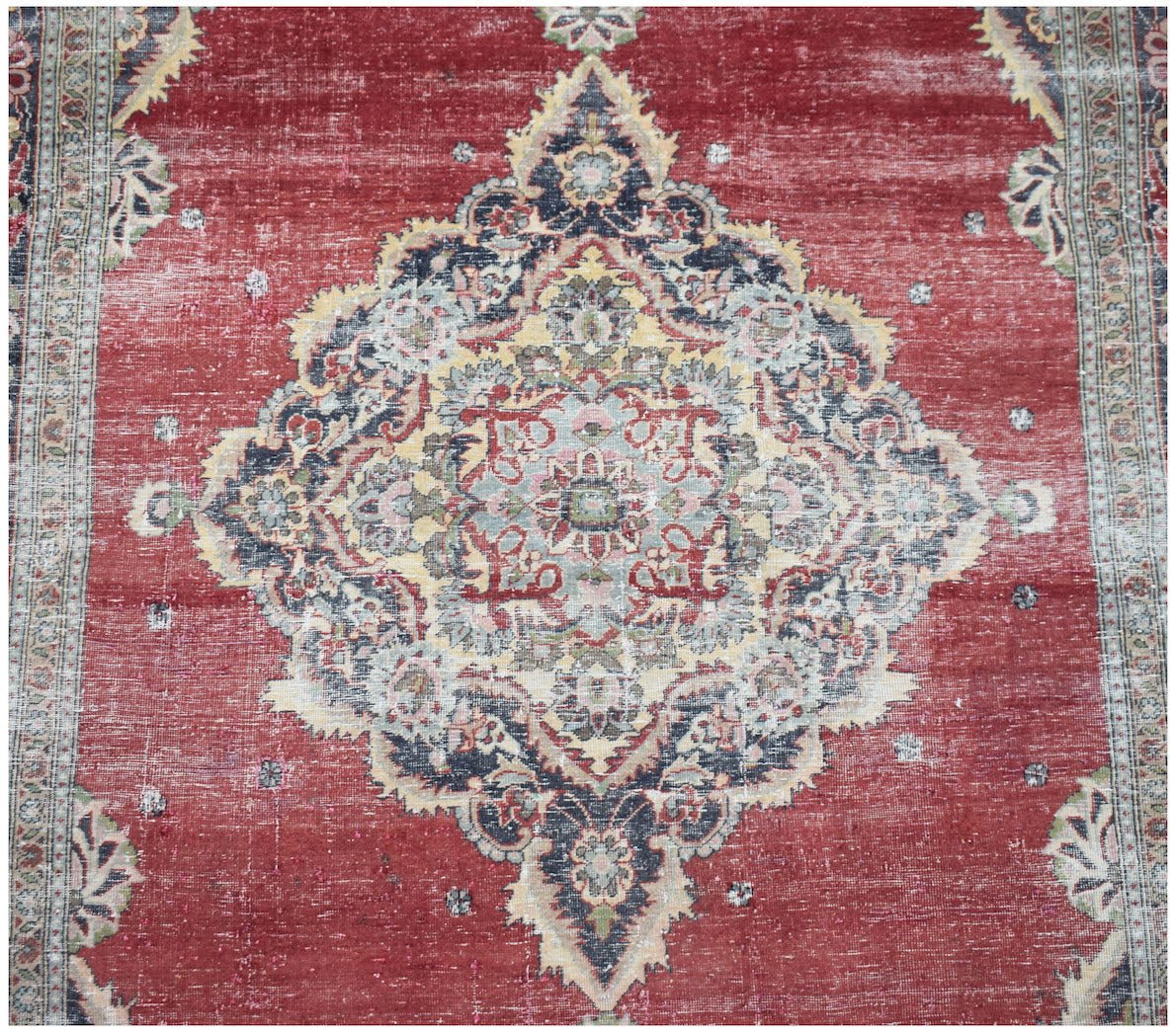 A vintage Persian Kerman rug featuring a central floral medallion on a red field.
