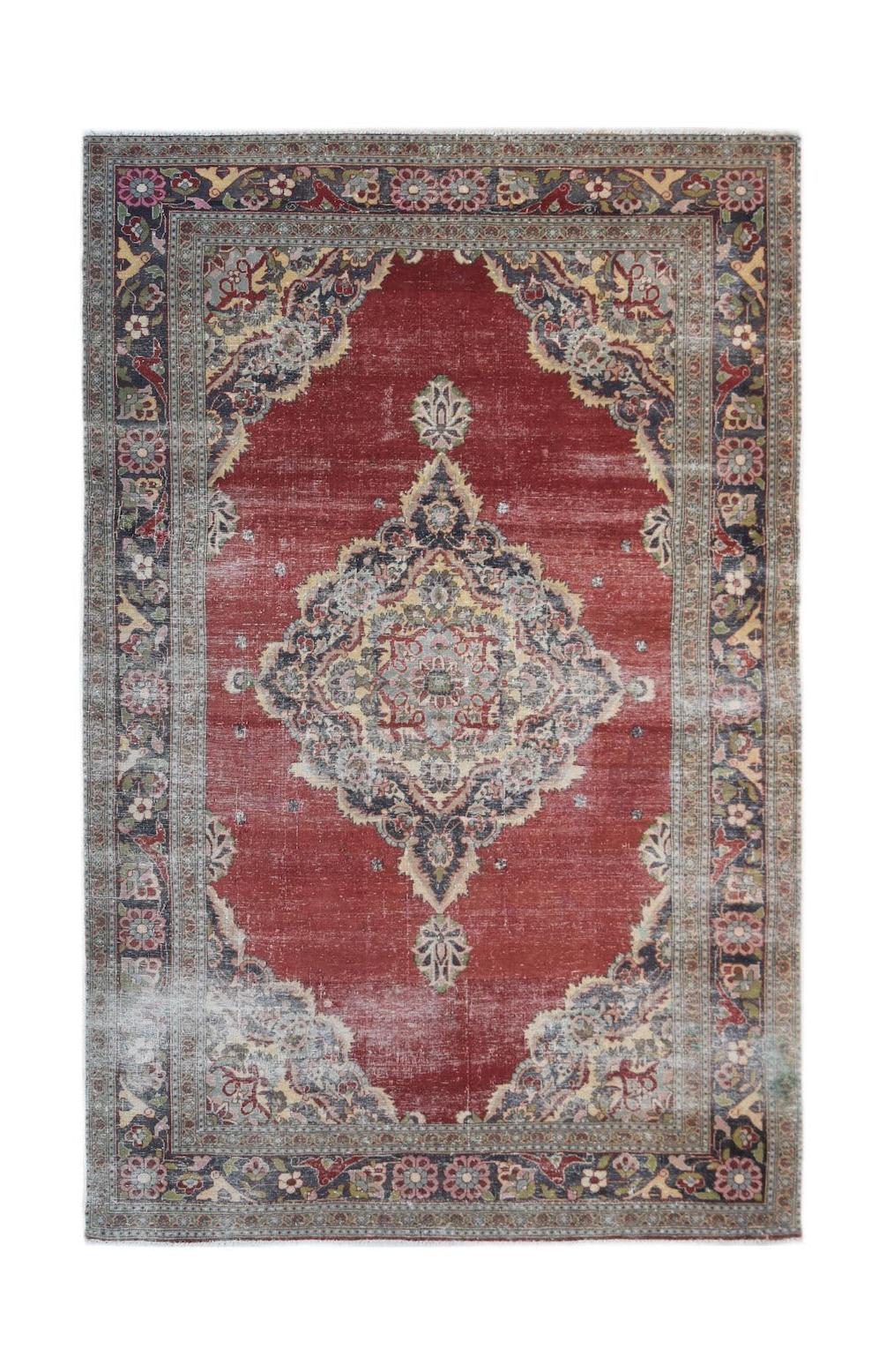 A vintage Persian Kerman rug featuring a central medallion and intricate floral patterns in red.
